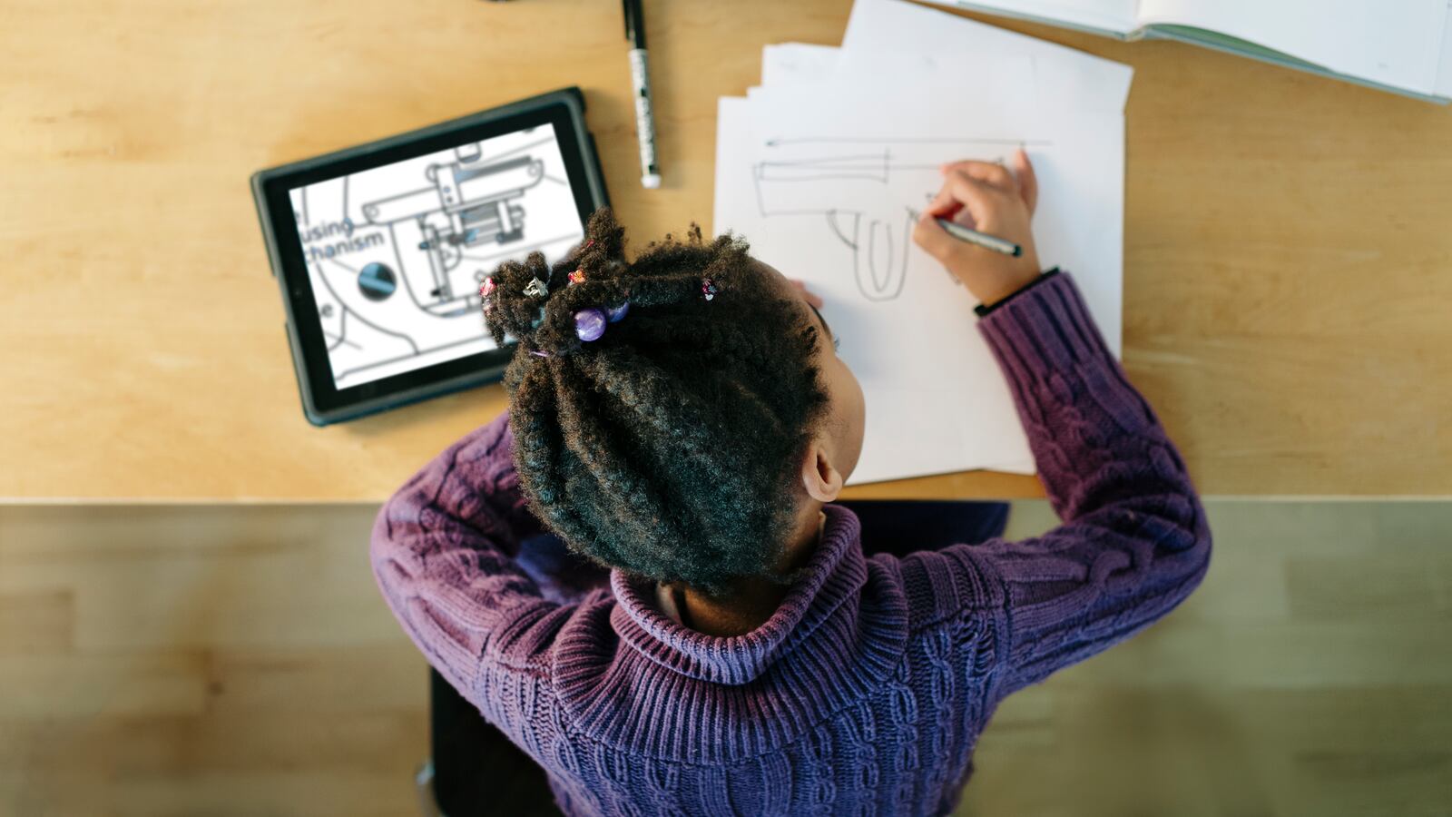 Child sitting at a table working on a new idea for a toy.