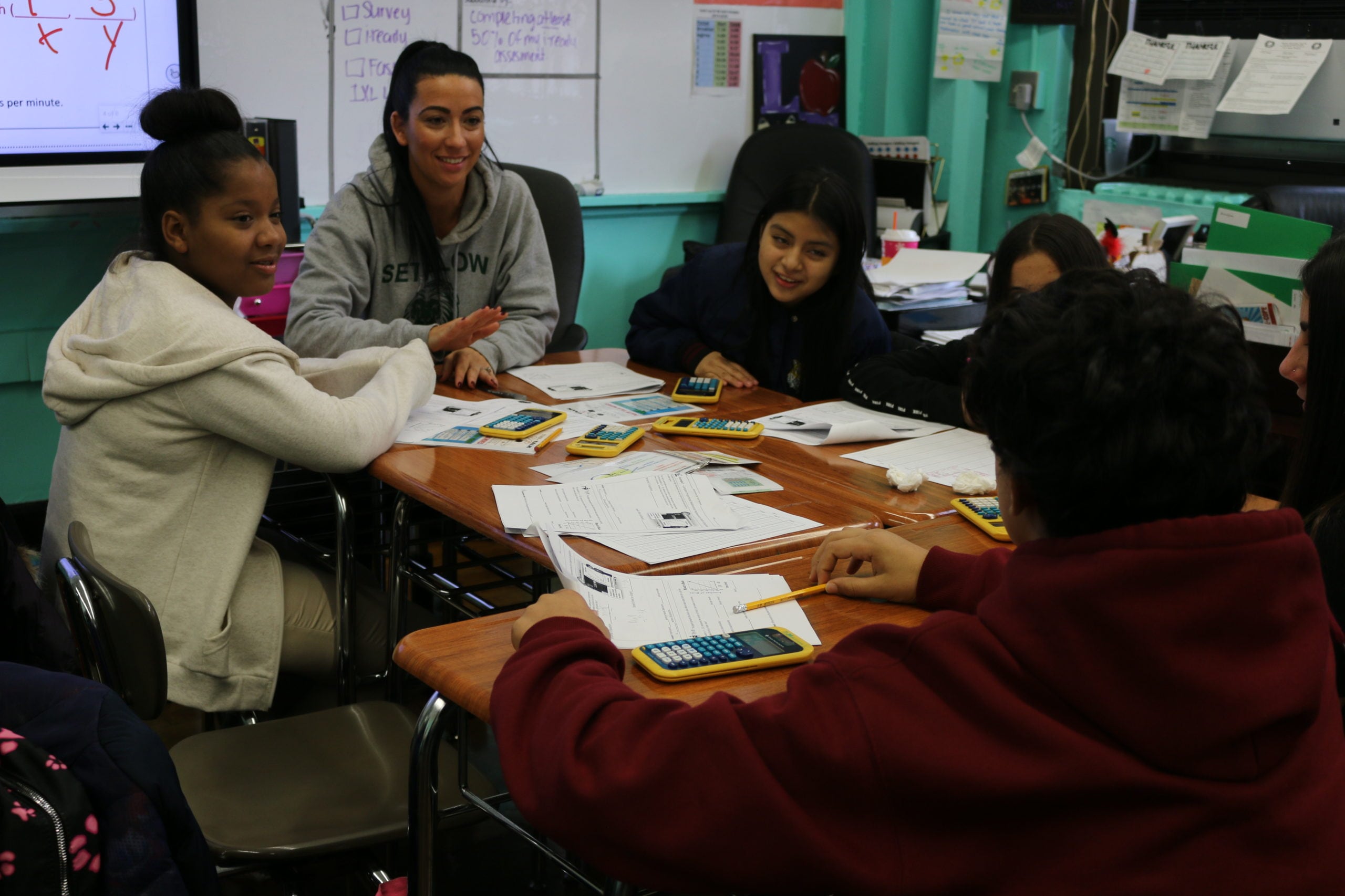An eighth-grade math teacher discusses a problem with students at I.S. 96 and encourages a student who is learning English as a new language to explain his answer. Roughly half of his peers are also learning the language.