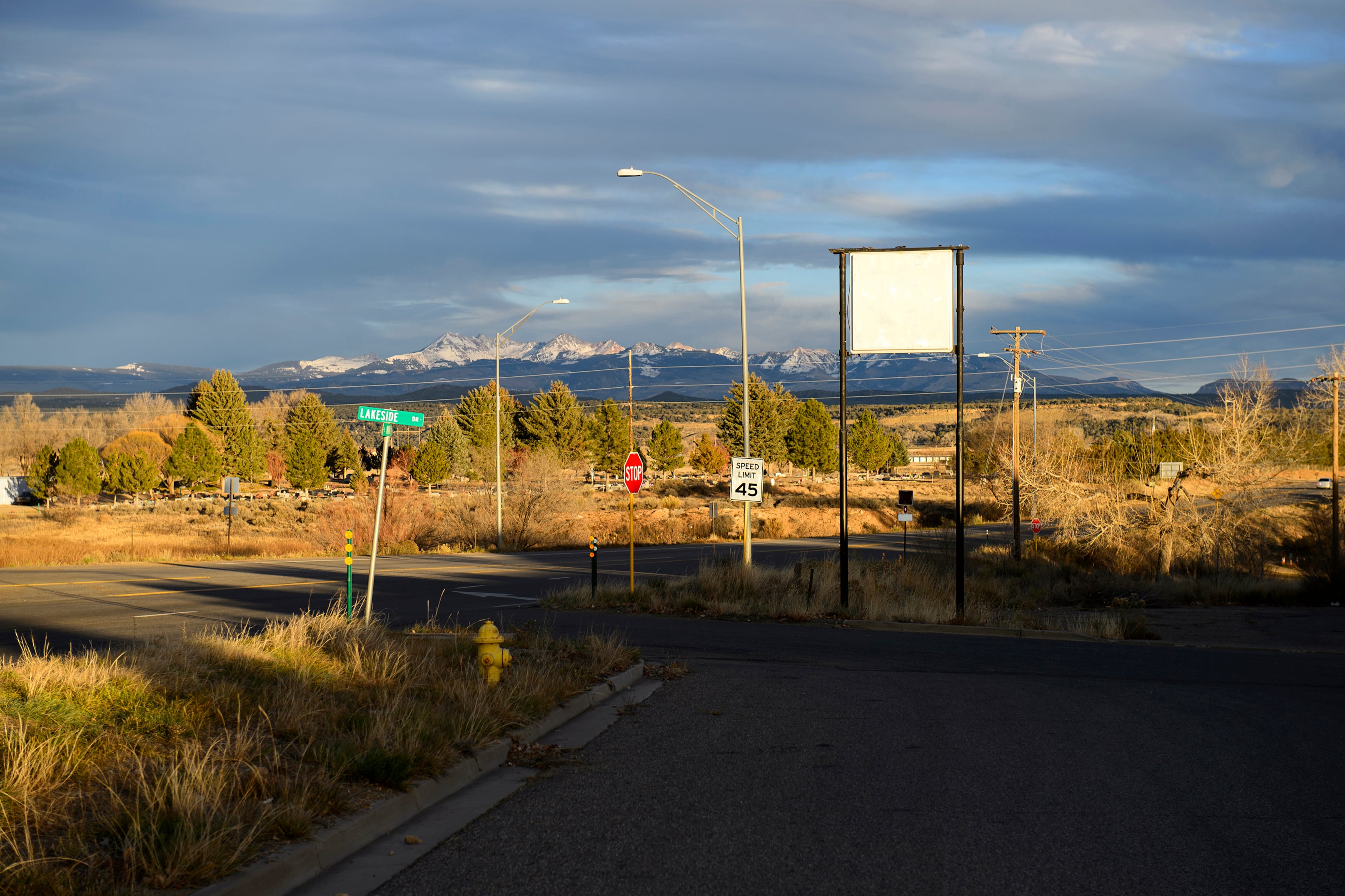 Road signs in the foreground and sunlight on the snowcapped mountains in the background.