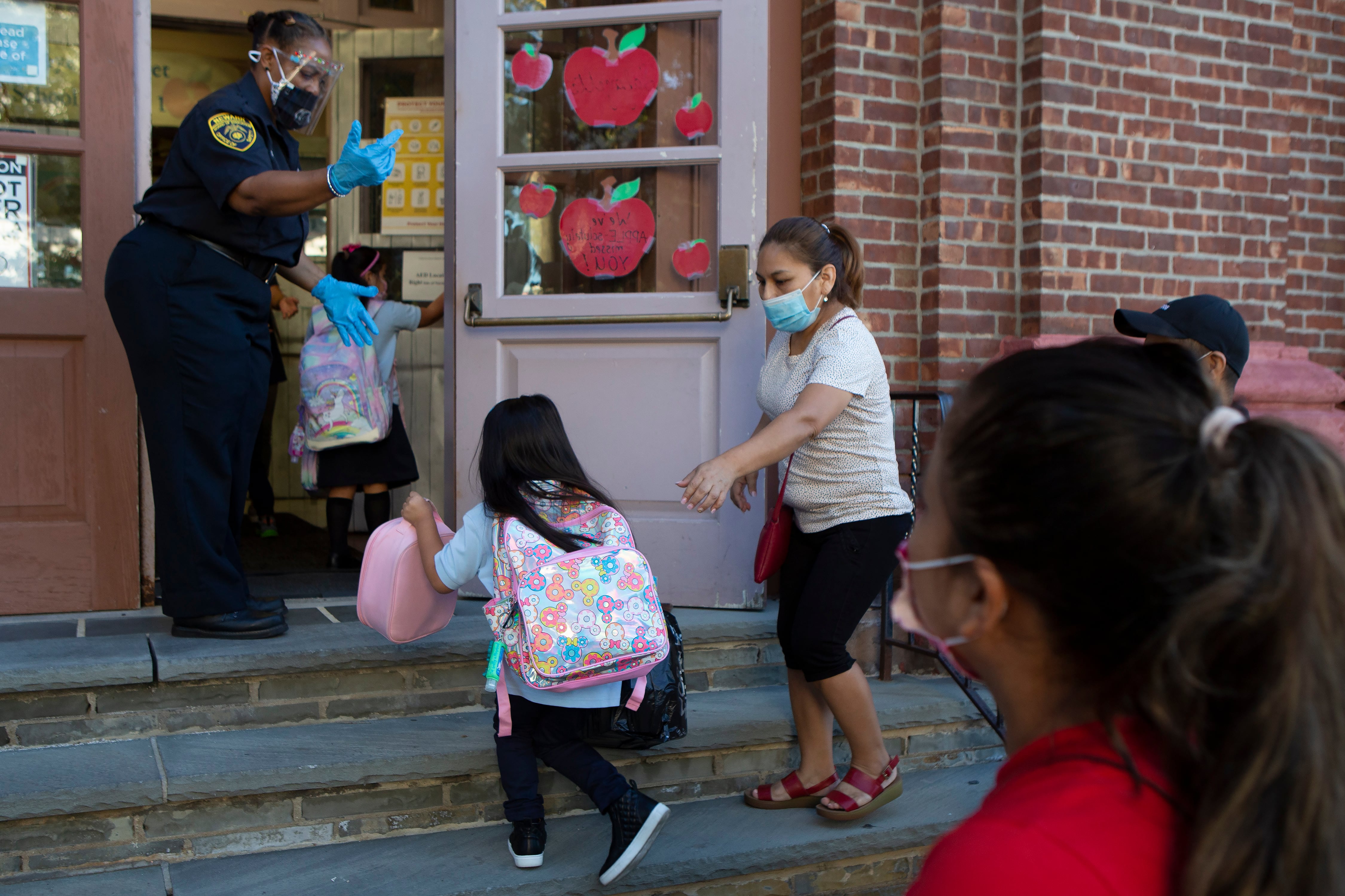 A school resource officer leads students into Newark’s Lafayette Street School on the first day of classes.