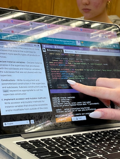A hand pointing to a screen on a computer.