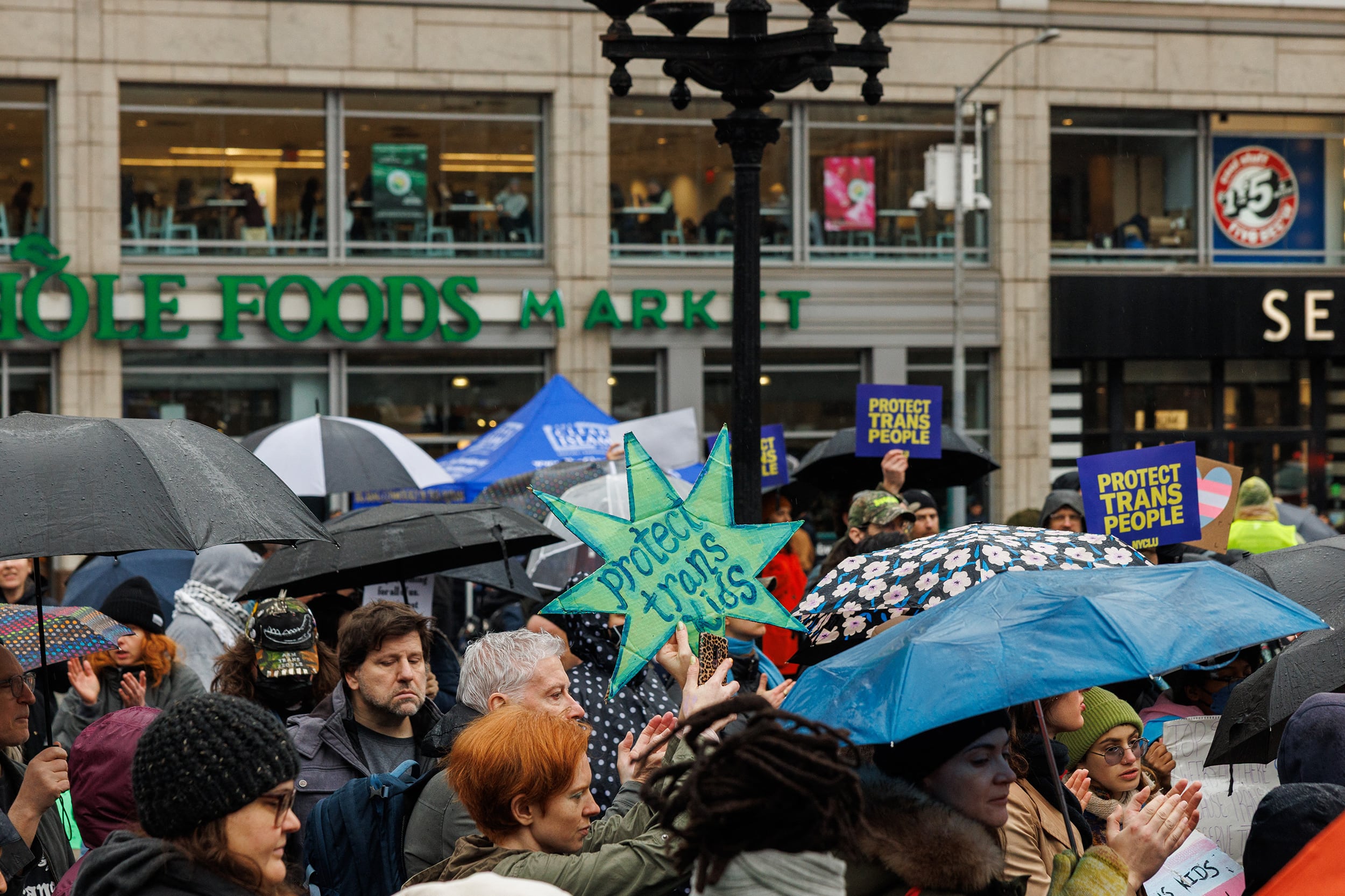A photograph of a large group of people protesting and rallying for trans rights in New York City.