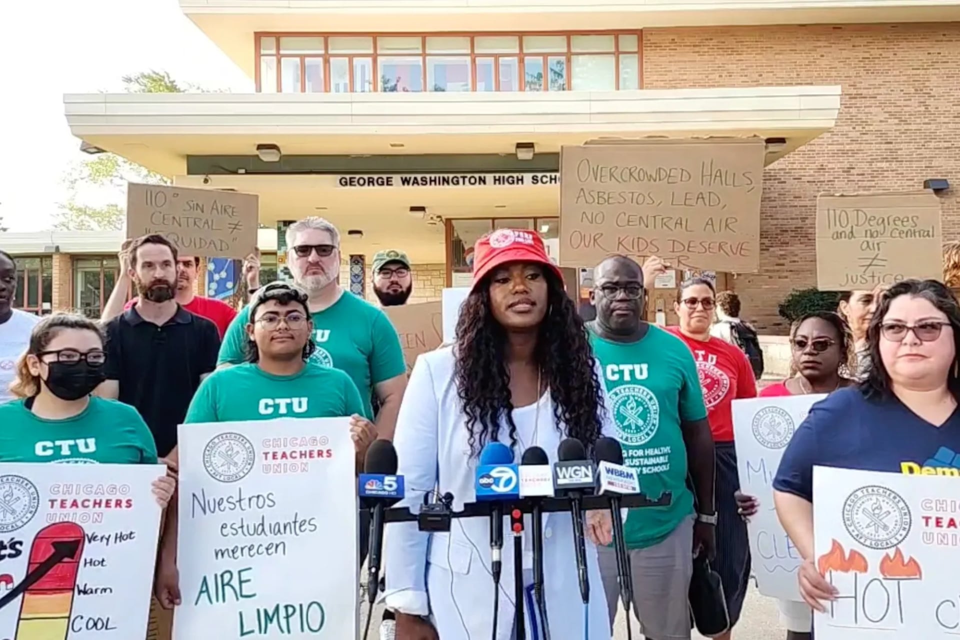 Chicago Teachers Union President Stacy Davis Gates stands behind microphones and next to parents and teachers holding signs outside George Washington High School.