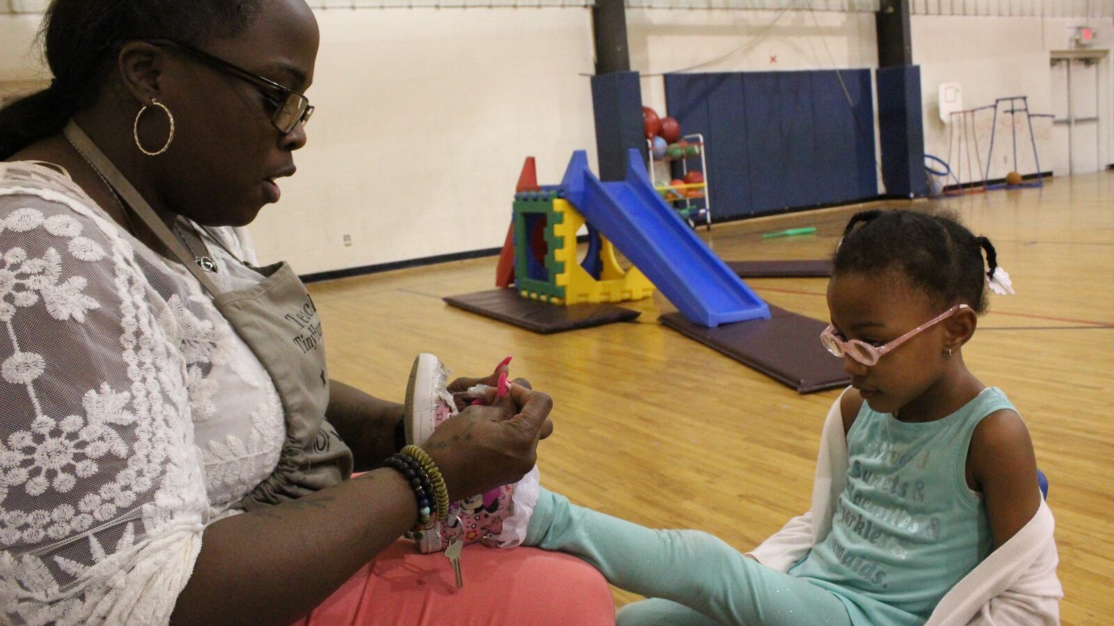 Cindy Lester, ties a shoelace during gym class at Children of the Rising Sun Empowerment Center in northwest Detroit.