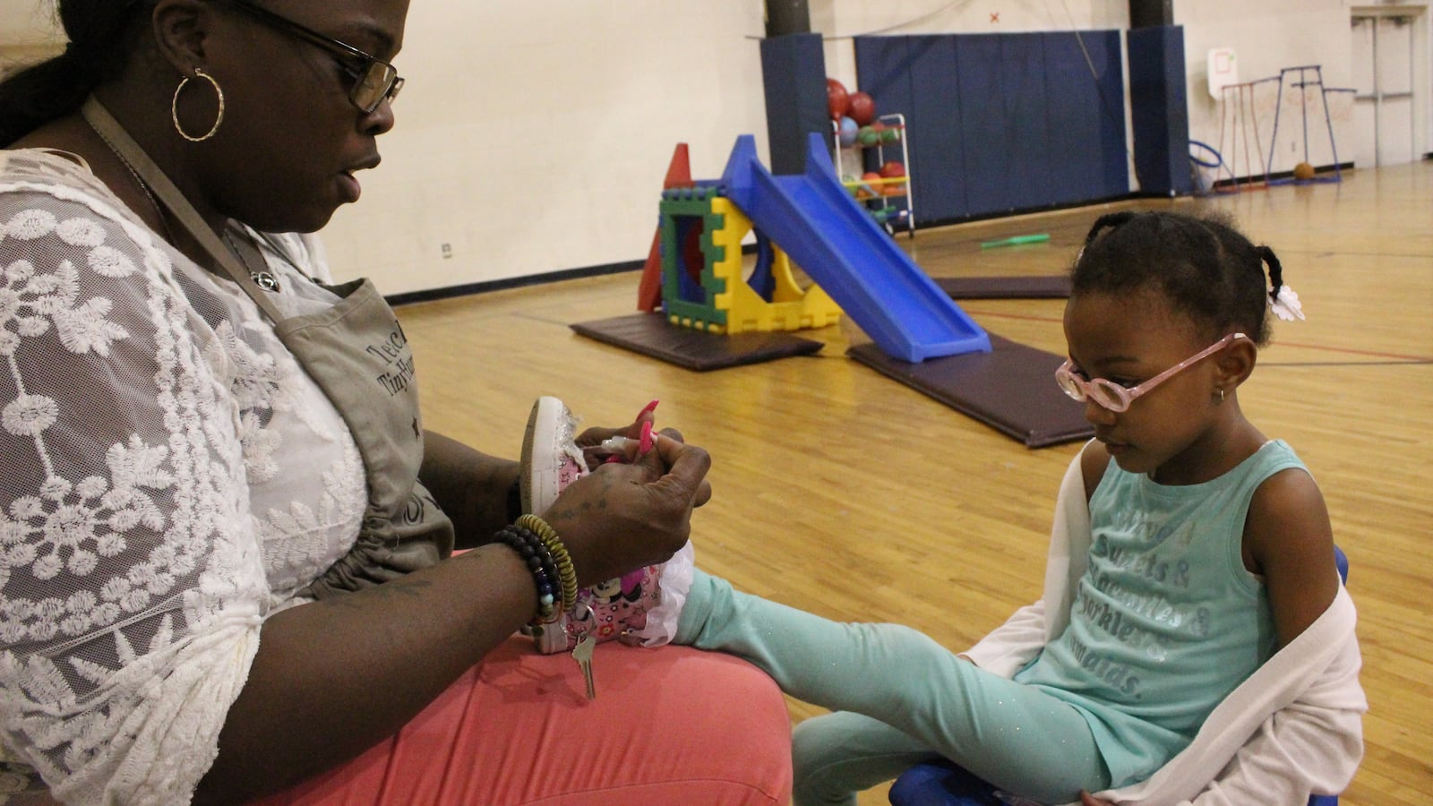 Cindy Lester, ties a shoelace during gym class at Children of the Rising Sun Empowerment Center in northwest Detroit.