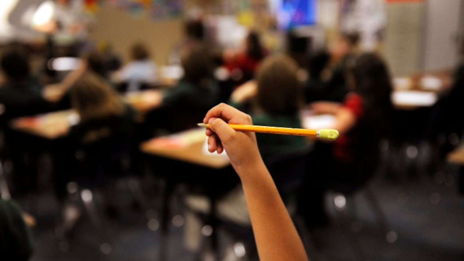 A student holds up a pencil with a yellow eraser.