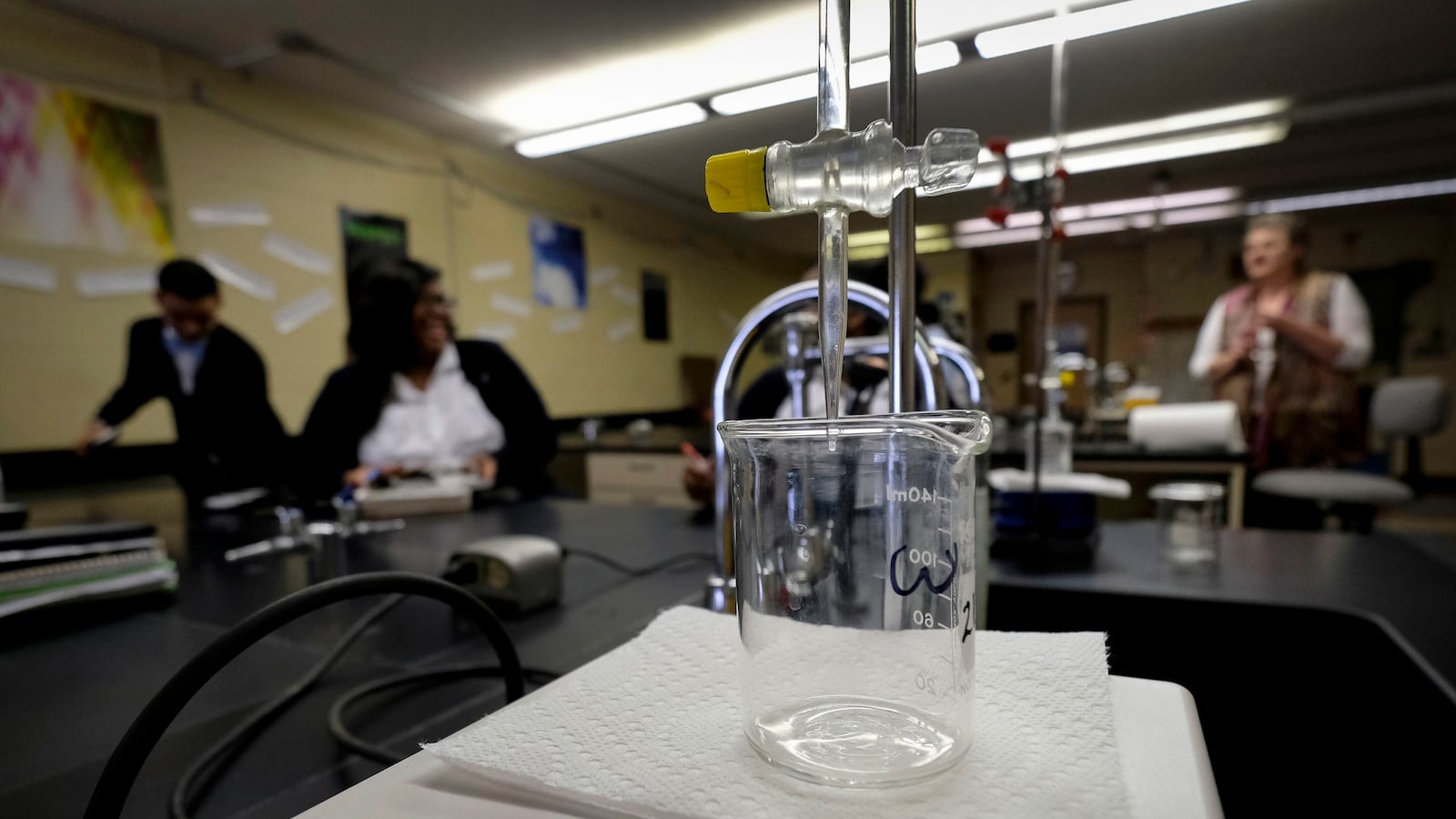 Students sit in the background of a science experiment in a school laboratory.