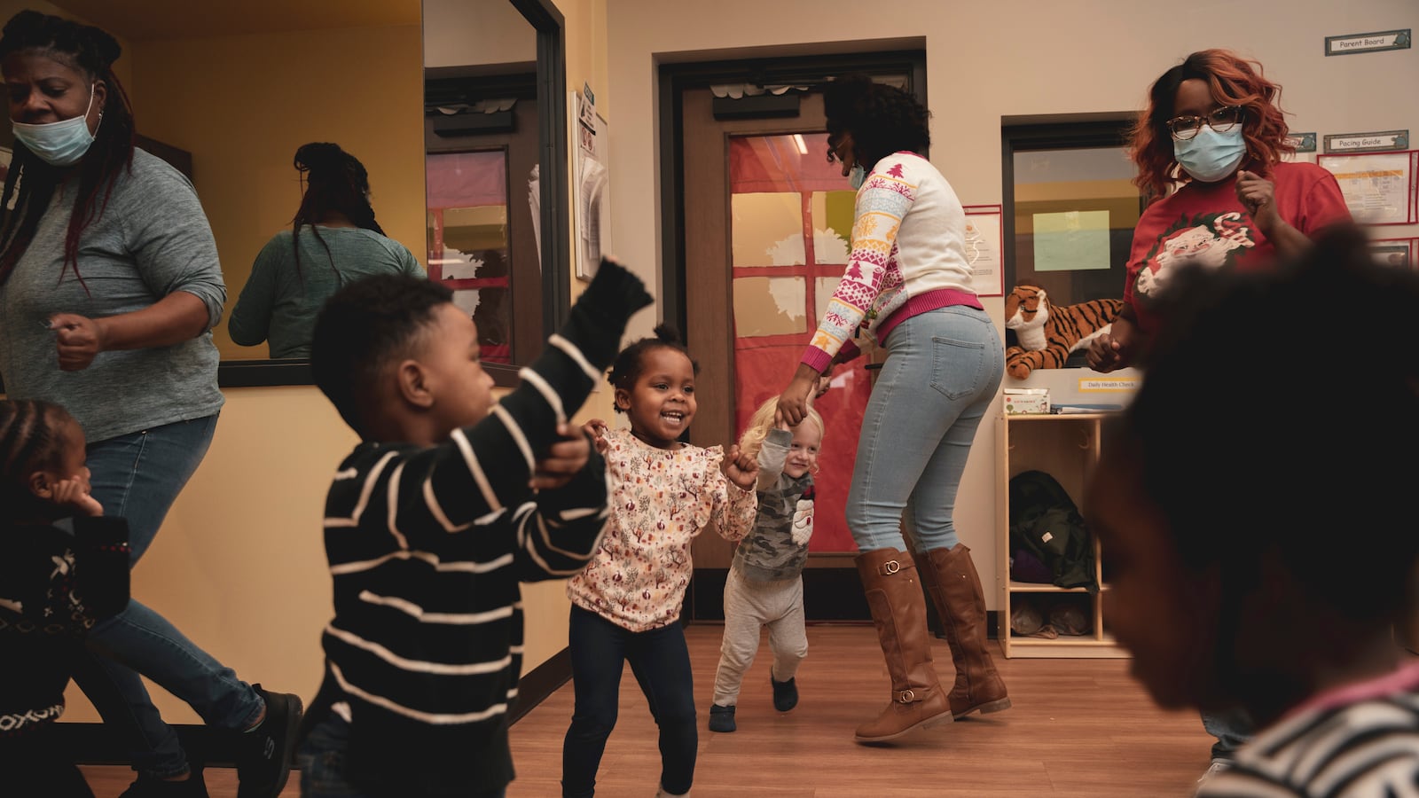 Teachers play and dance with their young students in a classroom.