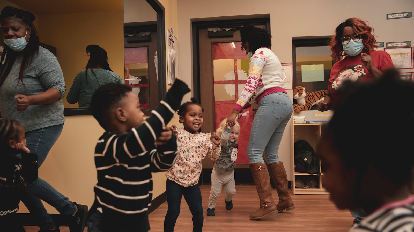 Teachers play and dance with their young students in a classroom.