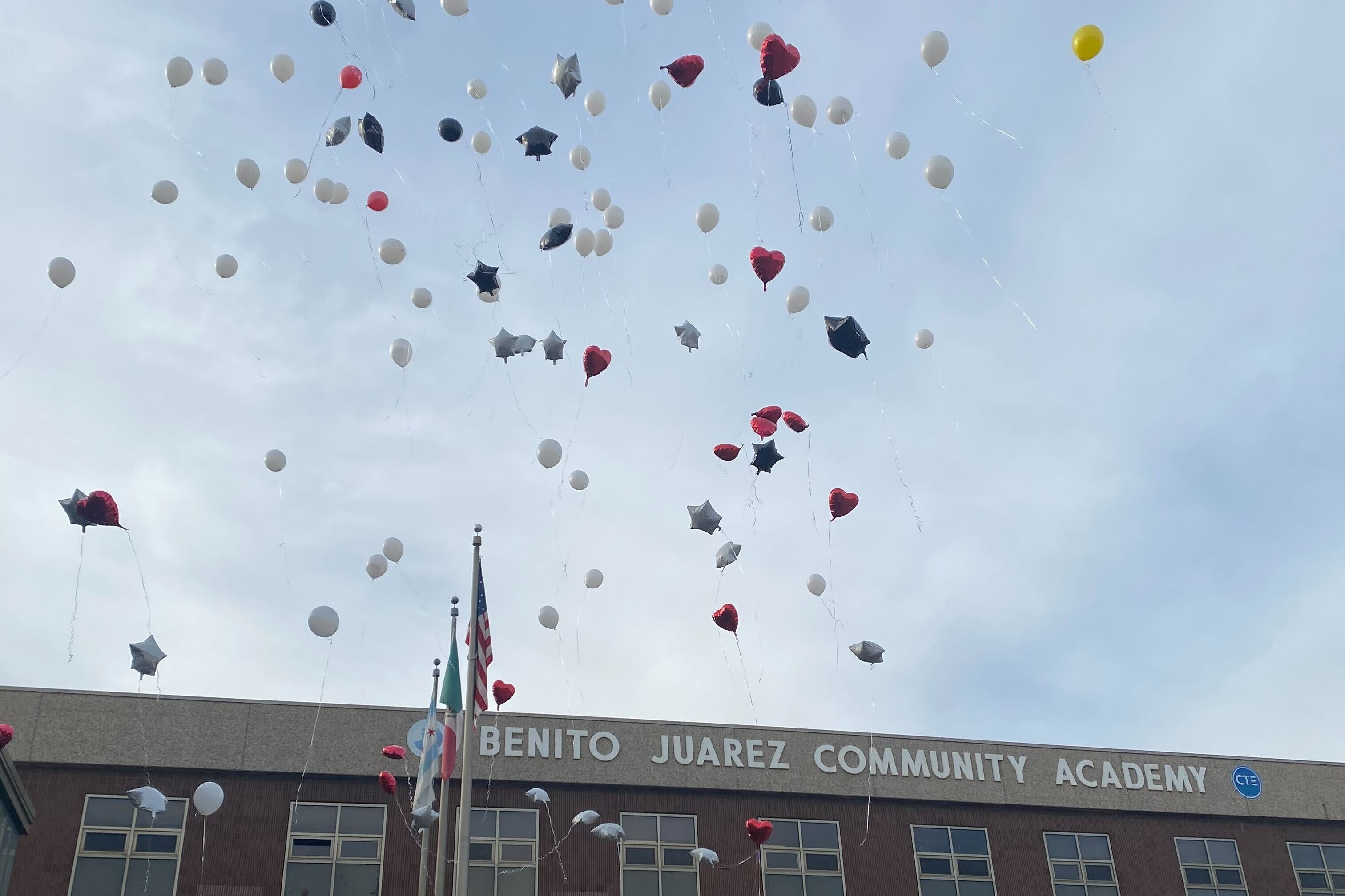 White, red, and black balloons float up to the sky outside Benito Juarez Community Academy in Chicago.