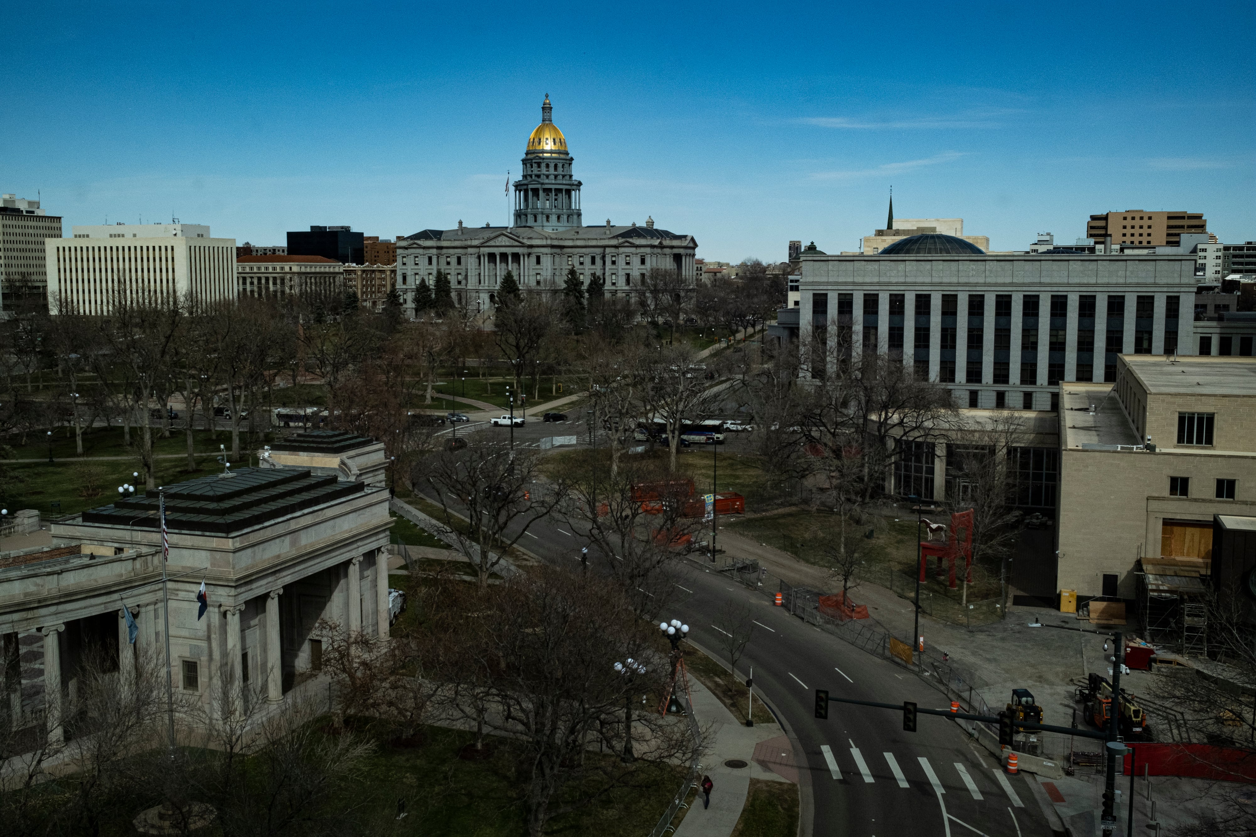 The Colorado State Capitol is seen from some distance, surrounded by other buildings, its dome glowing slightly.