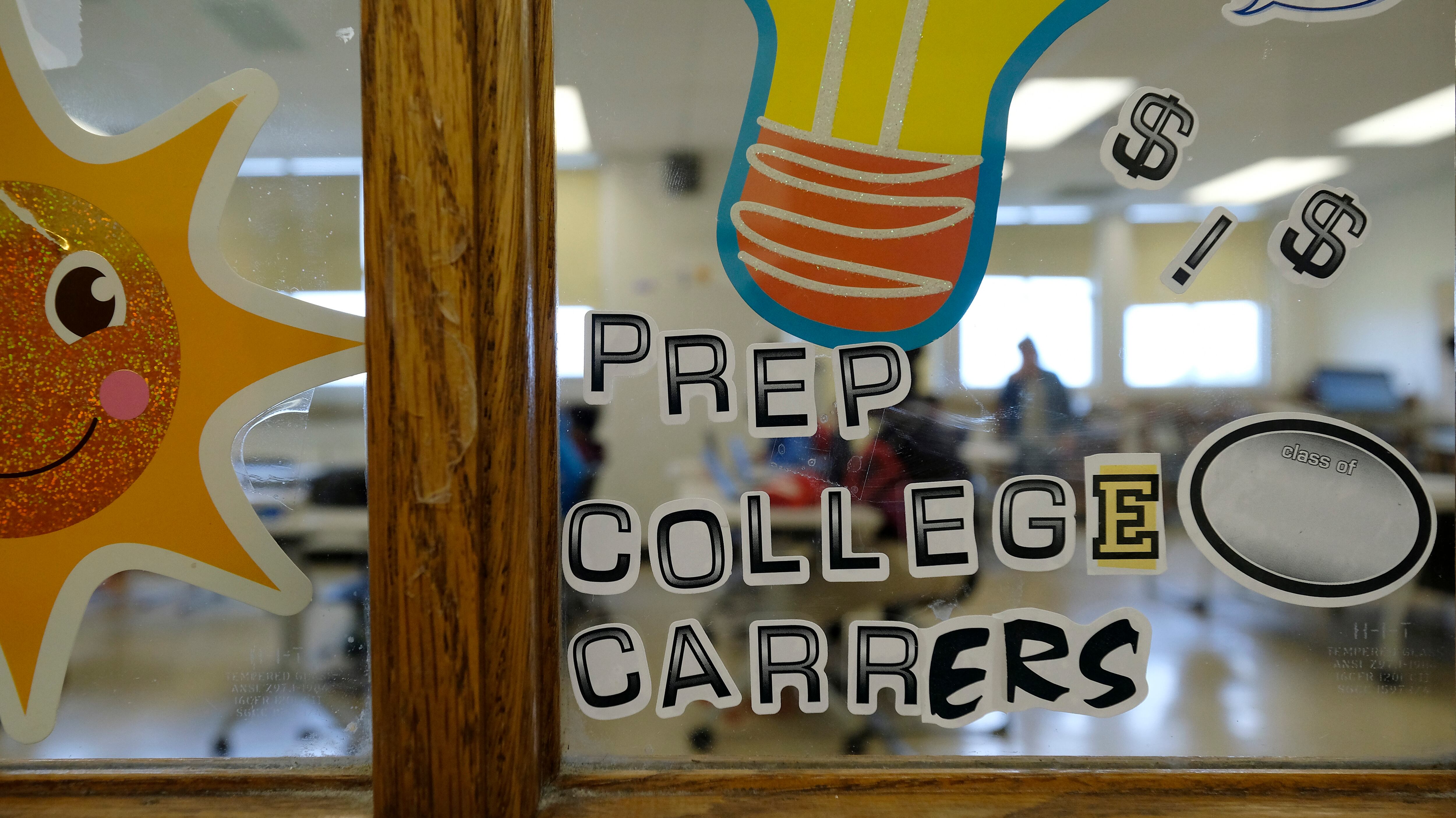 Bright letters on a window inside of a school spell "Prep College Careers" along with a drawing of a smiling sun and a lightbulb.