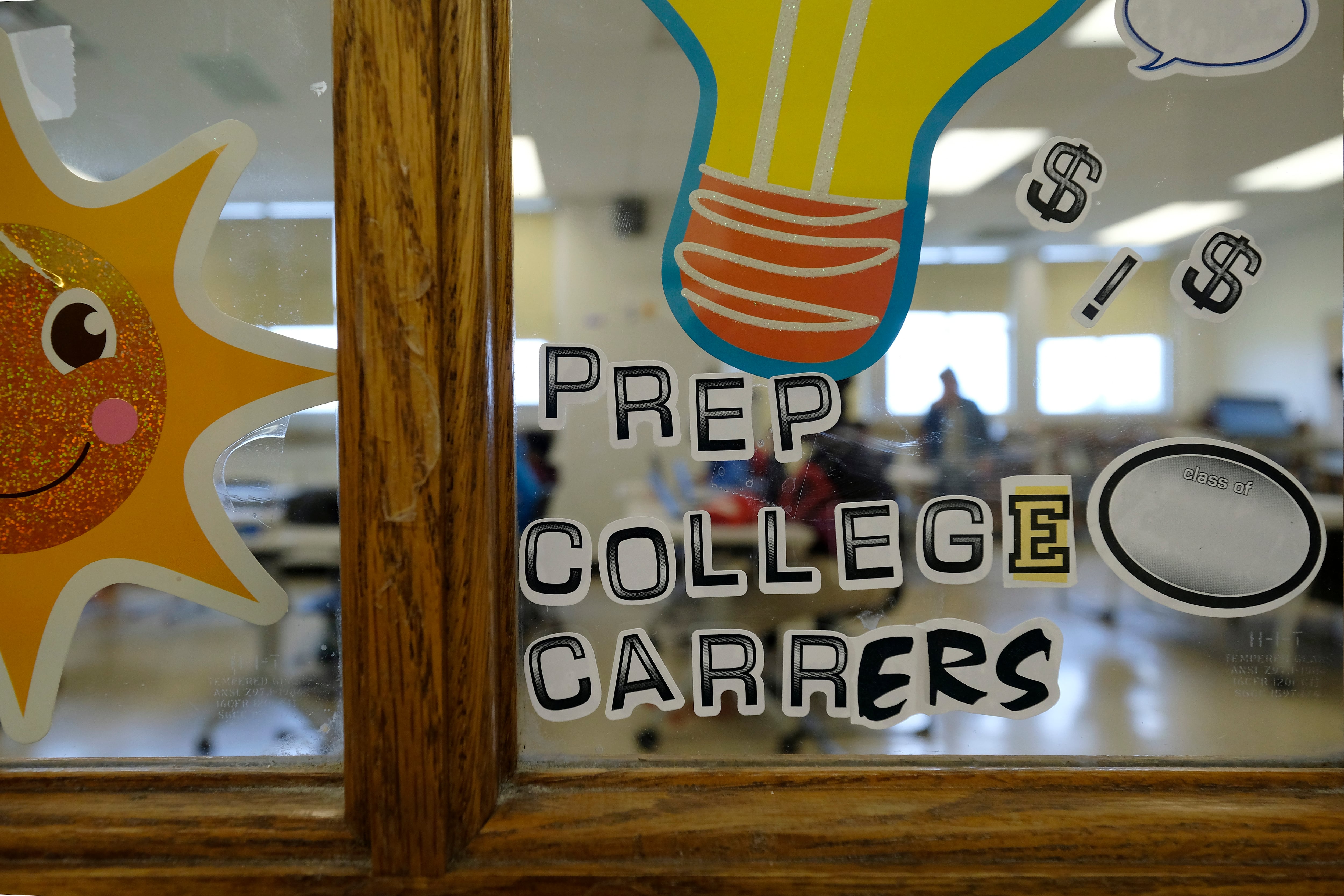 Bright letters on a window inside of a school spell "Prep College Careers" along with a drawing of a smiling sun and a lightbulb.