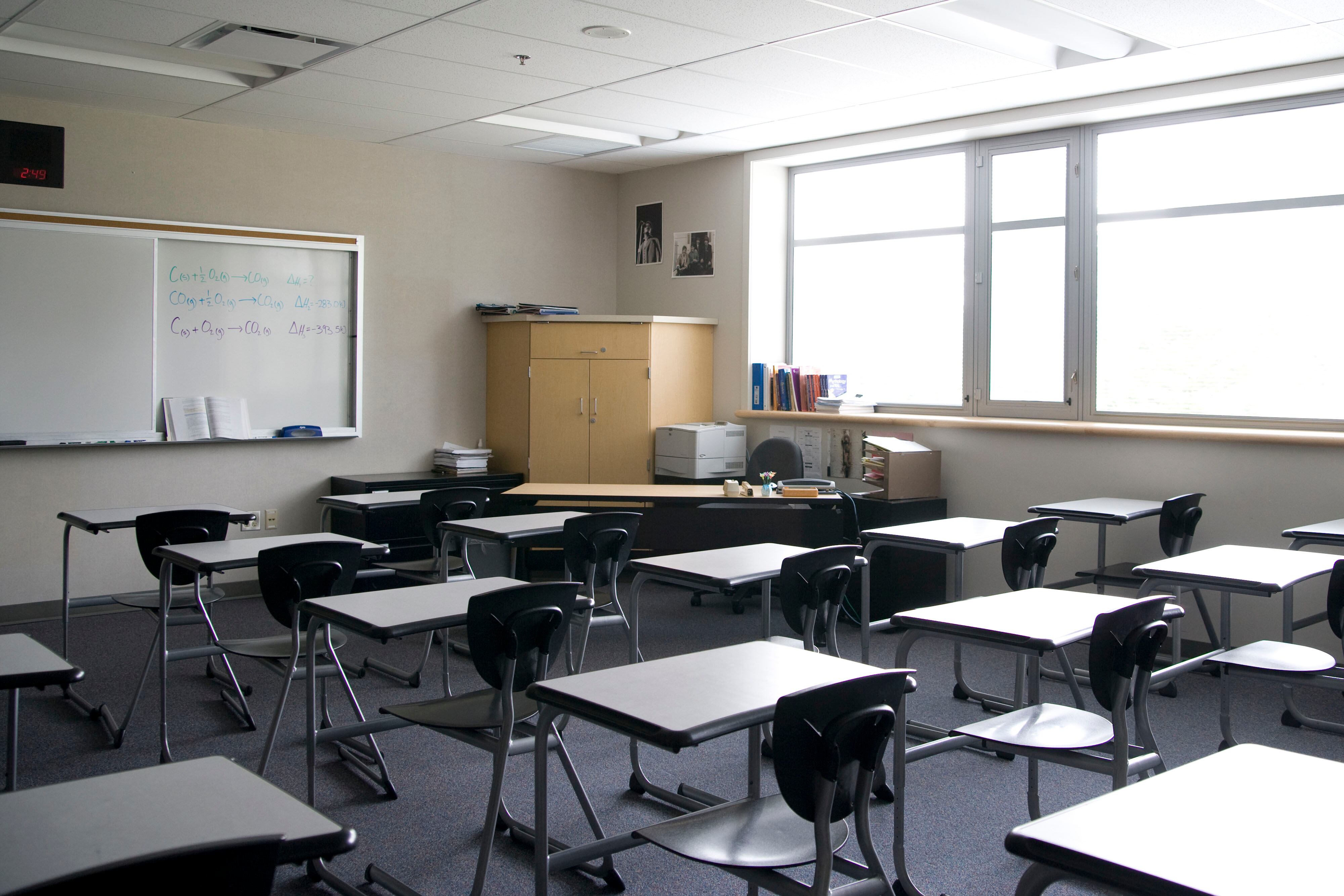 An empty high school classroom with chairs and desks in rows.