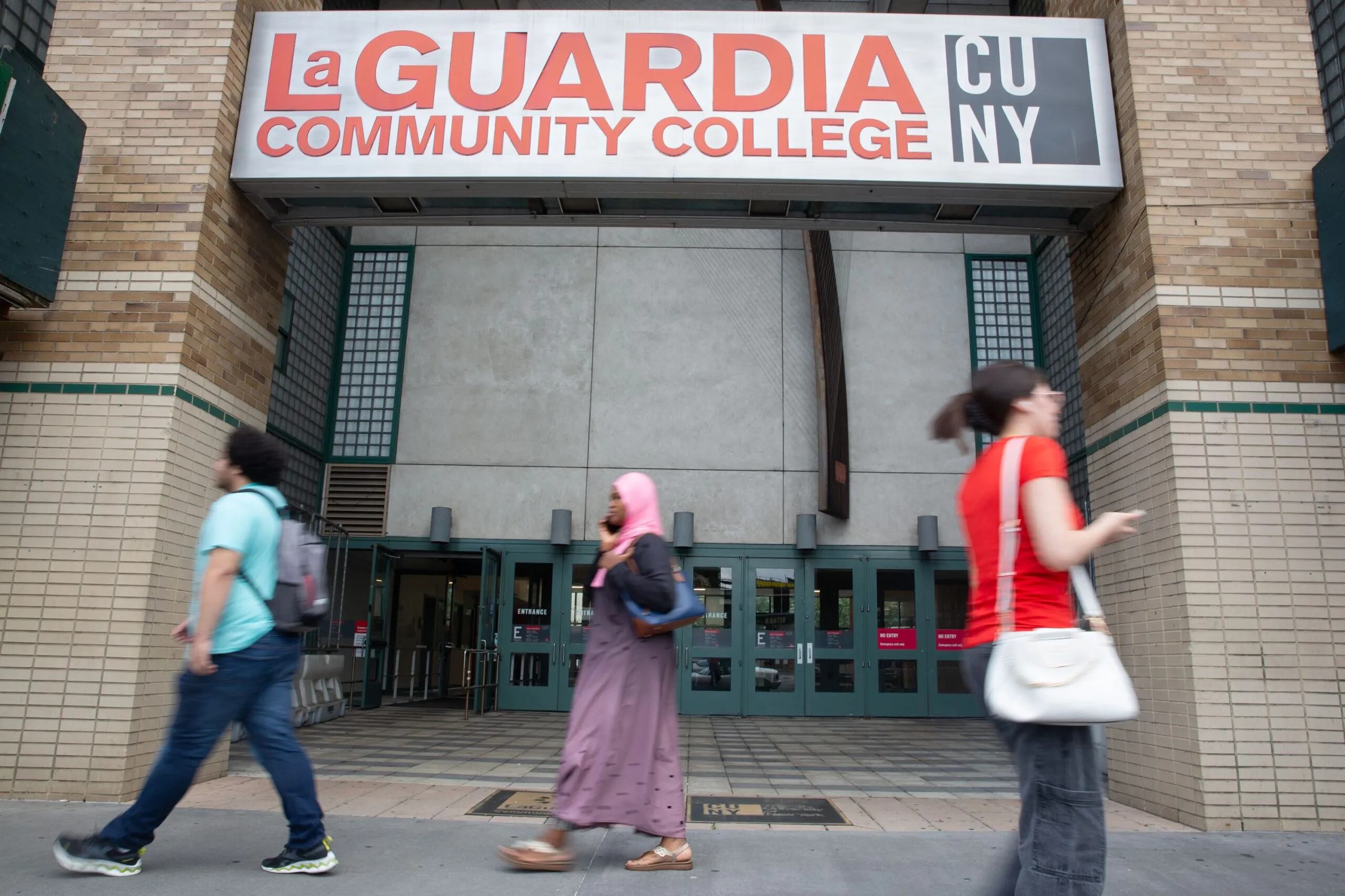 Students walk in front of a college building.