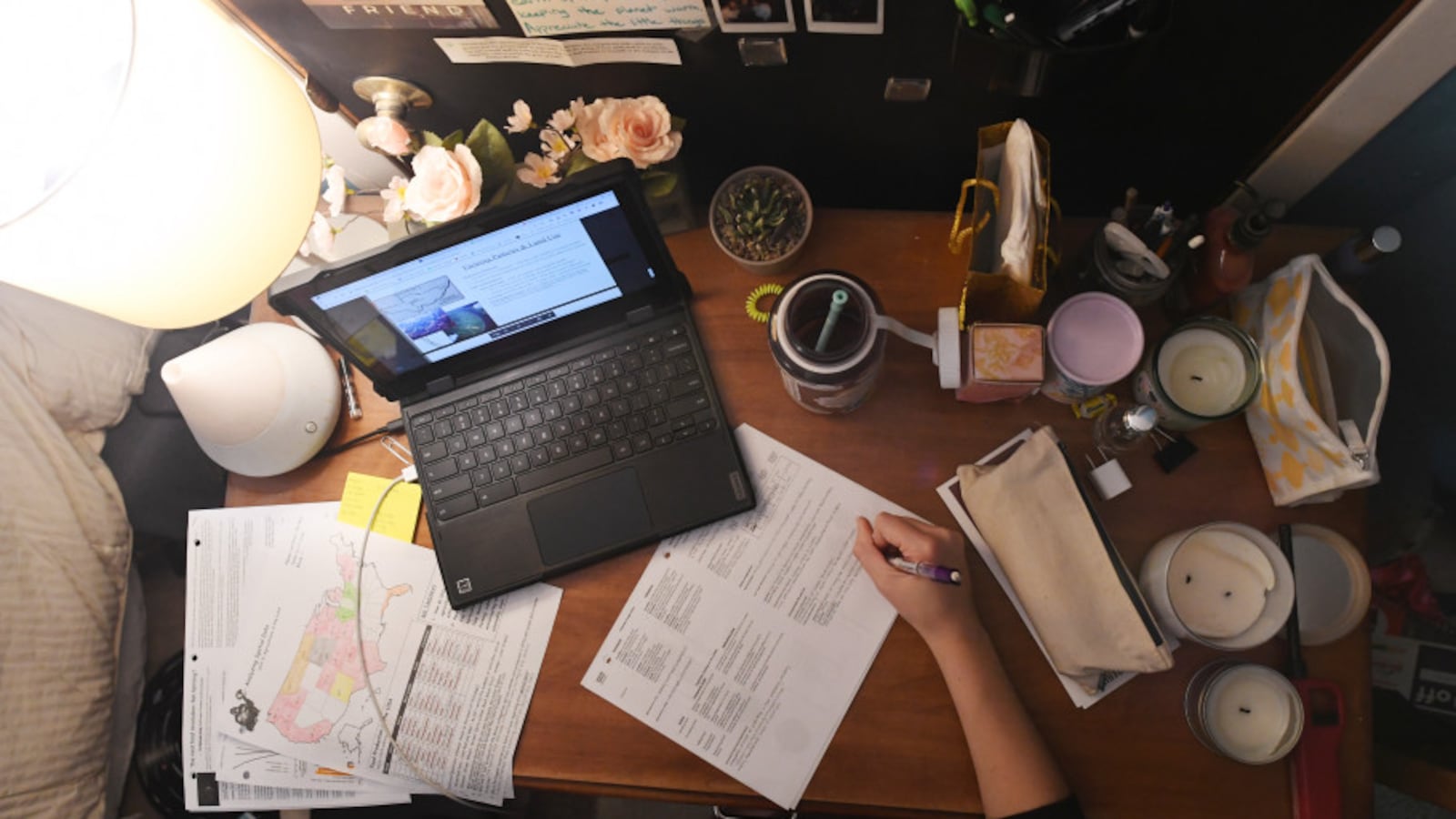 Bird’s-eye view of a high school student’s home desk with a laptop, coffee cup, and papers.