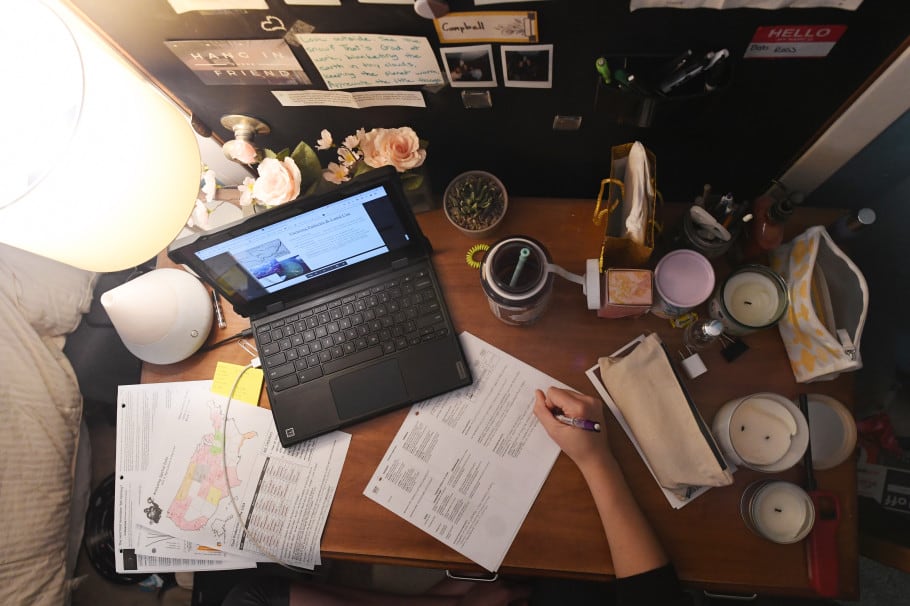 Bird’s-eye view of a high school student’s home desk with a laptop, coffee cup, and papers.