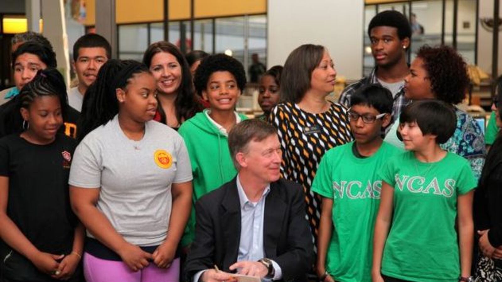 Gov. John Hickenlooper, surrounded by students from DCIS Montbello and NCAS - Noel Community Arts School, signs a bill changing Denver Public Schools' PERA contributions.