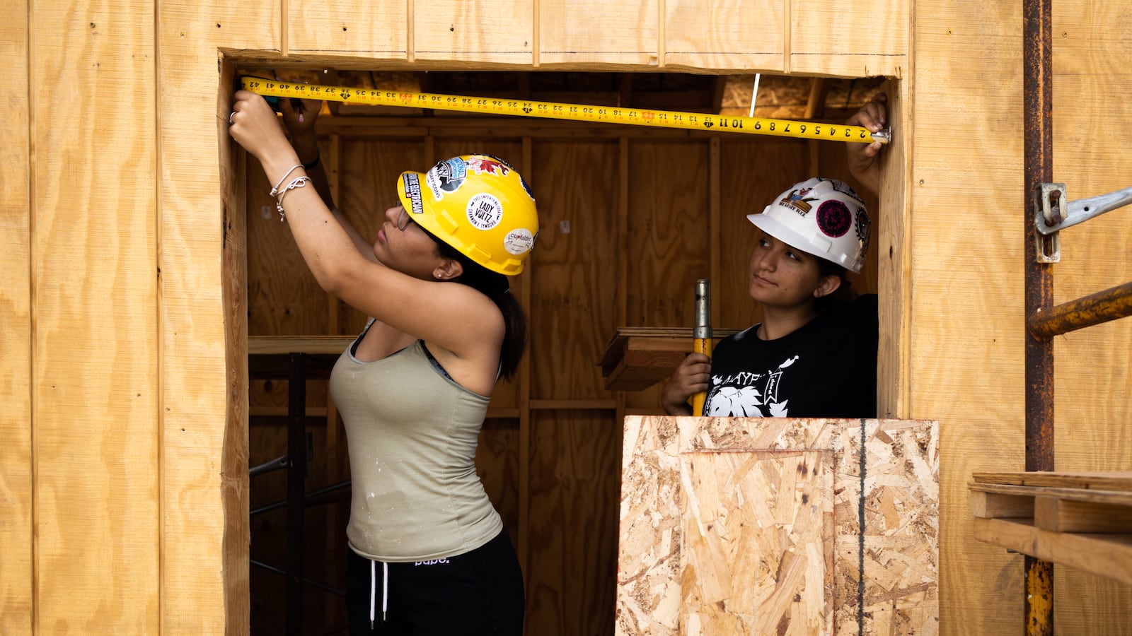 Students use a tape measure to see the width of the opening in a structure.