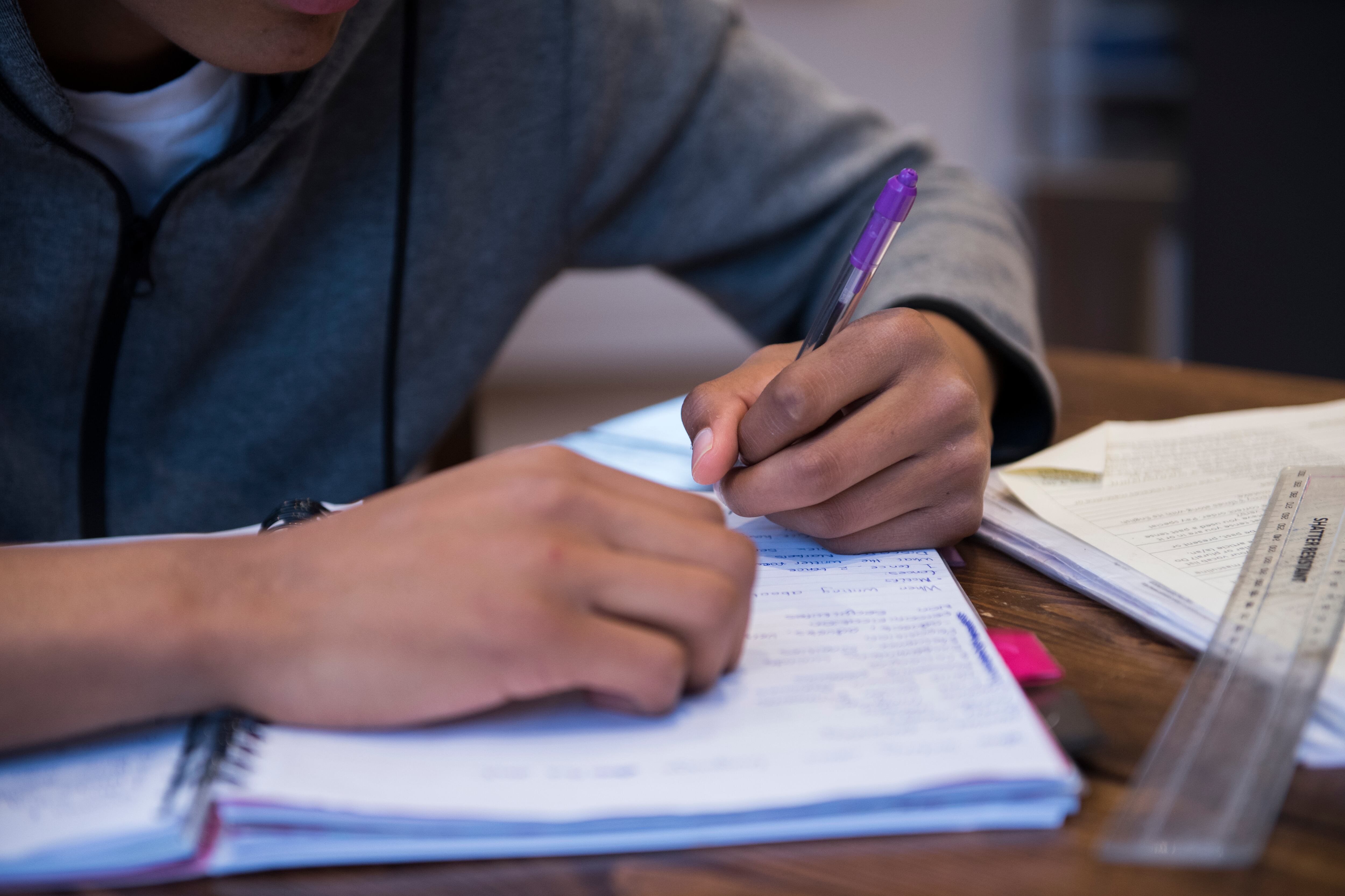 Close up on hands of student who is writing in a notebook.