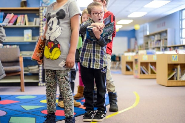 Vivian Elementary School third-grader Ayden Bobbitt, 9, reacts as he reads his book in the library checkout line Friday, Dec. 6, 2019, in Lakewood. Jeffco Public Schools.