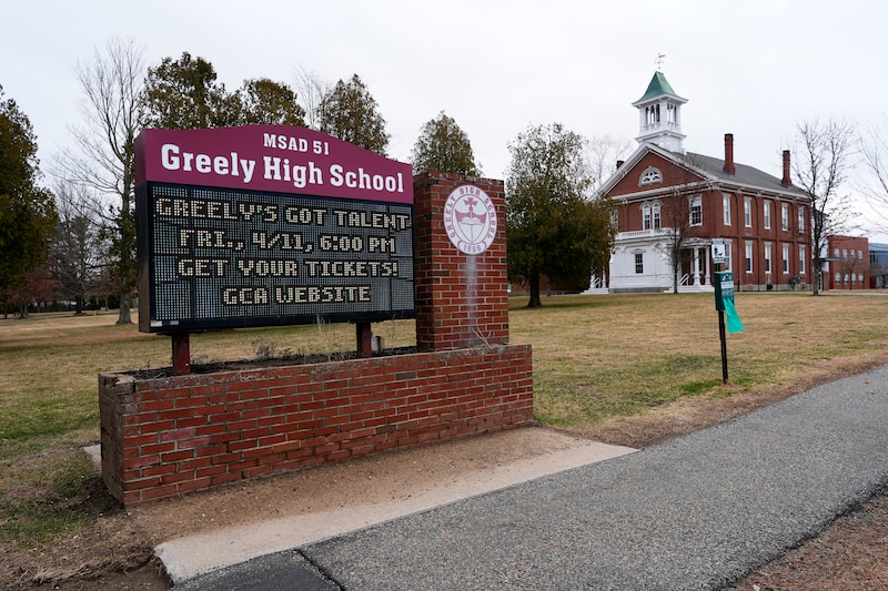 A large sign that reads "MSAD 51 Greely High School," sits in front of a school house.