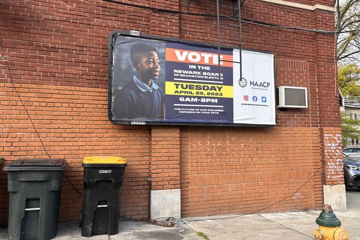 A sign urging people to vote hangs on a brick wall.