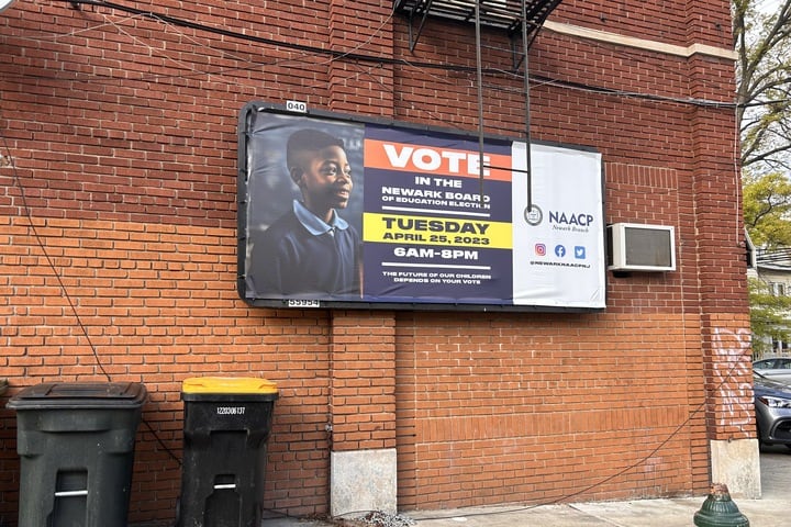 A sign urging people to vote hangs on a brick wall.