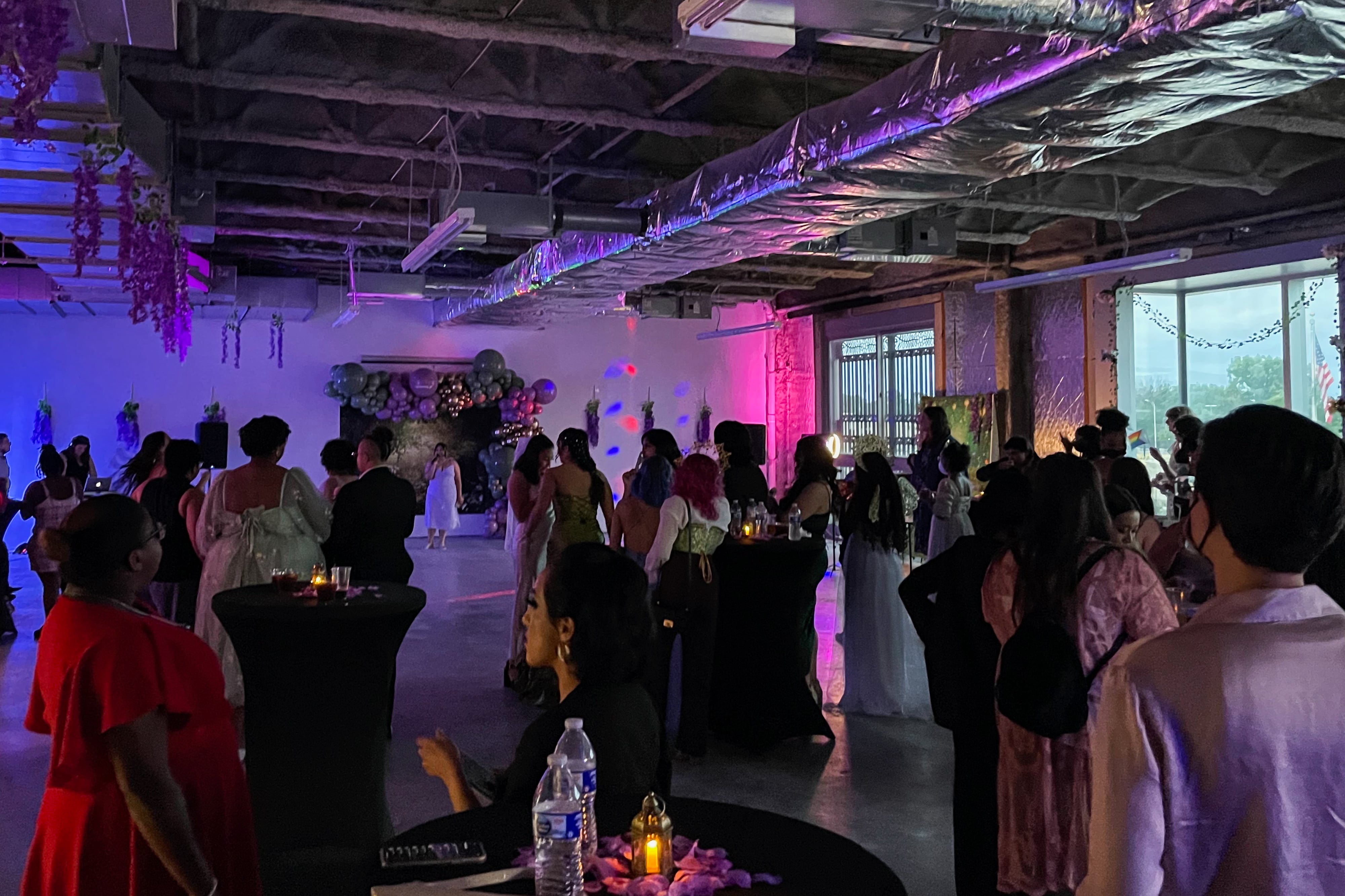 A crowd of people gather in a warehouse room for a dance.