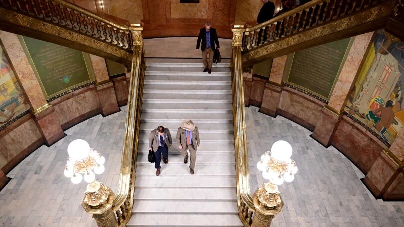 Colorado lawmakers walk down white steps in the Capitol.