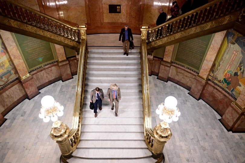 Colorado lawmakers walk down white steps in the Capitol.