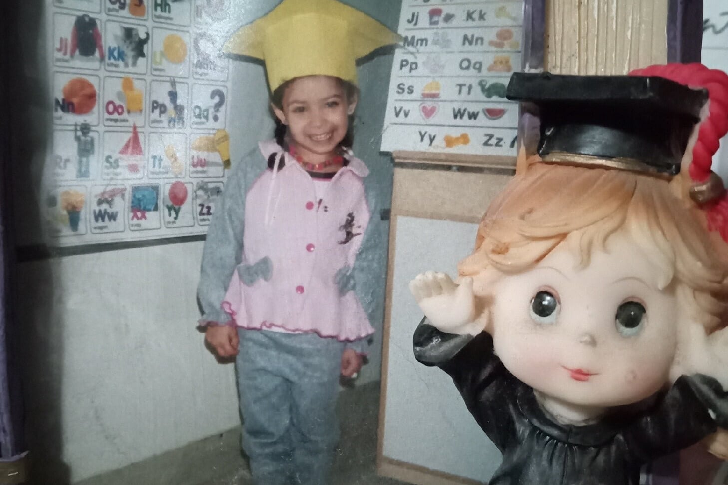 A young girl poses with a yellow graduation cap.