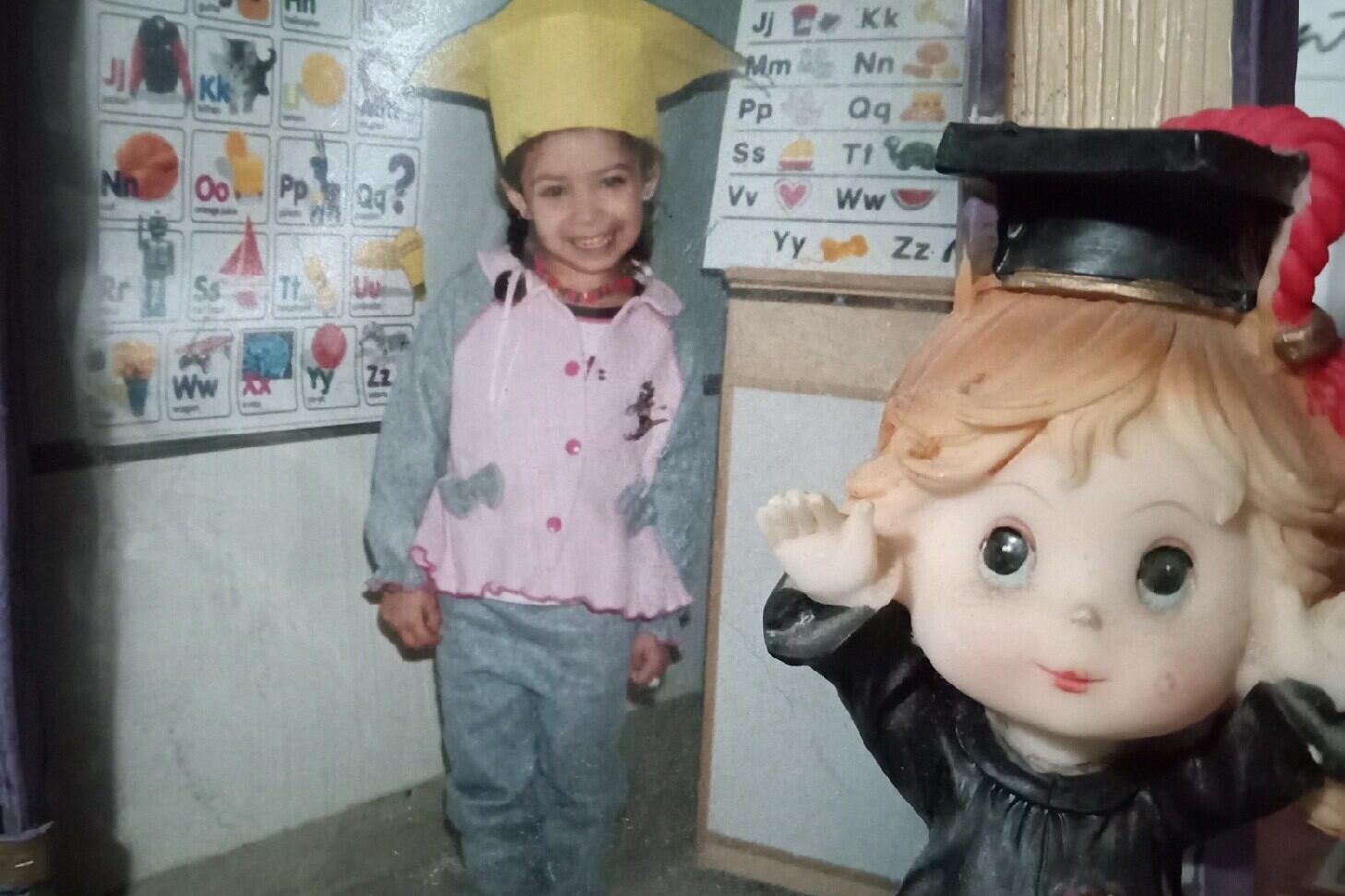 A young girl poses with a yellow graduation cap.