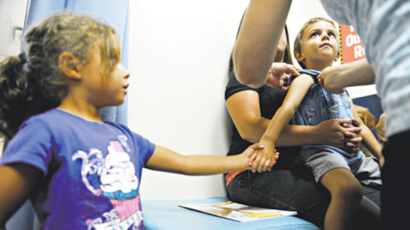 Nyah Ojeda, 6,  offers her hand to her four-year-old brother, Elija Ojeda, while nurses prepare him for a round of vaccinations in 2012.