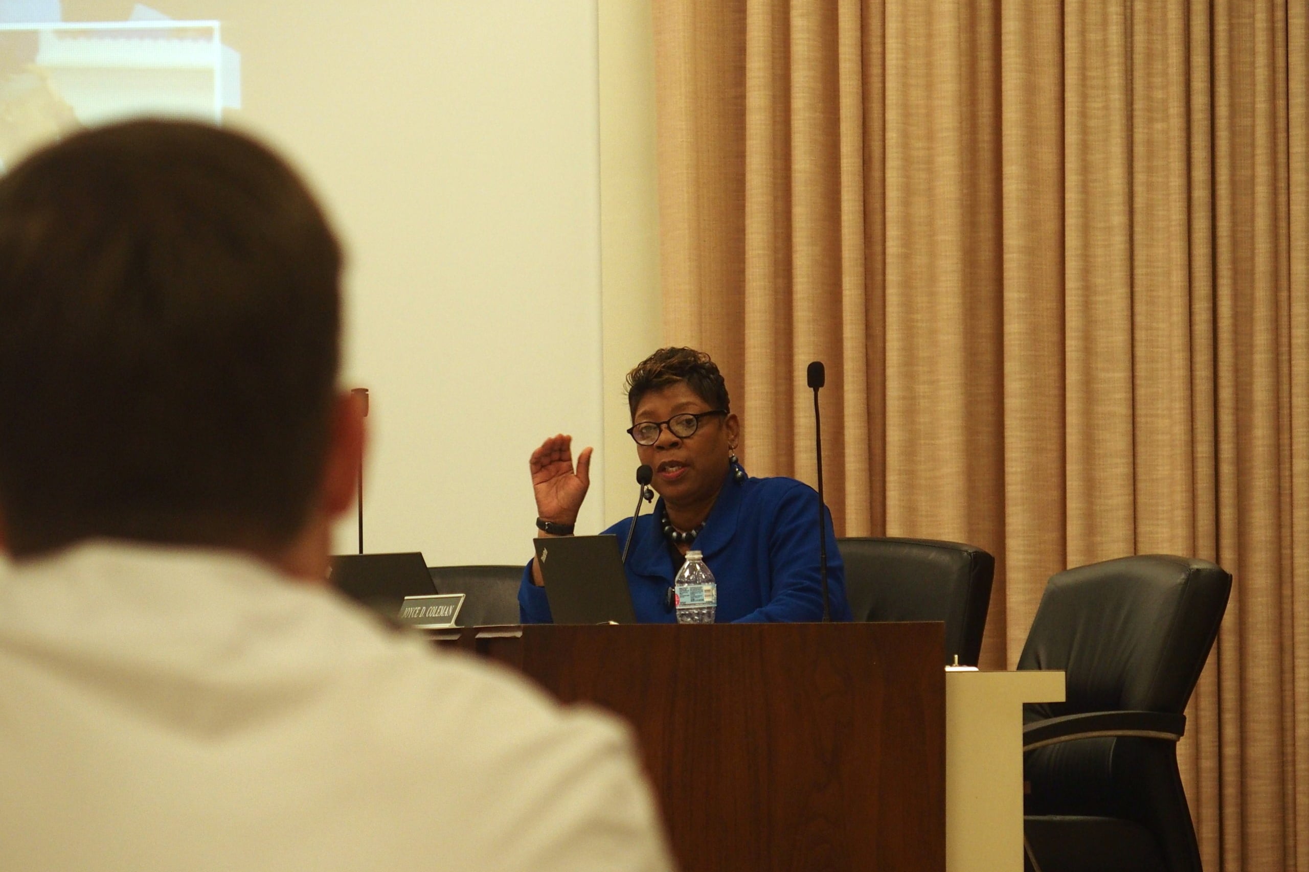 A woman, Shelby County Schools board member Althea Greene, is in a blue outfit seated behind a table and speaks during a hearing for Veritas College Preparatory, a charter school in South Memphis.