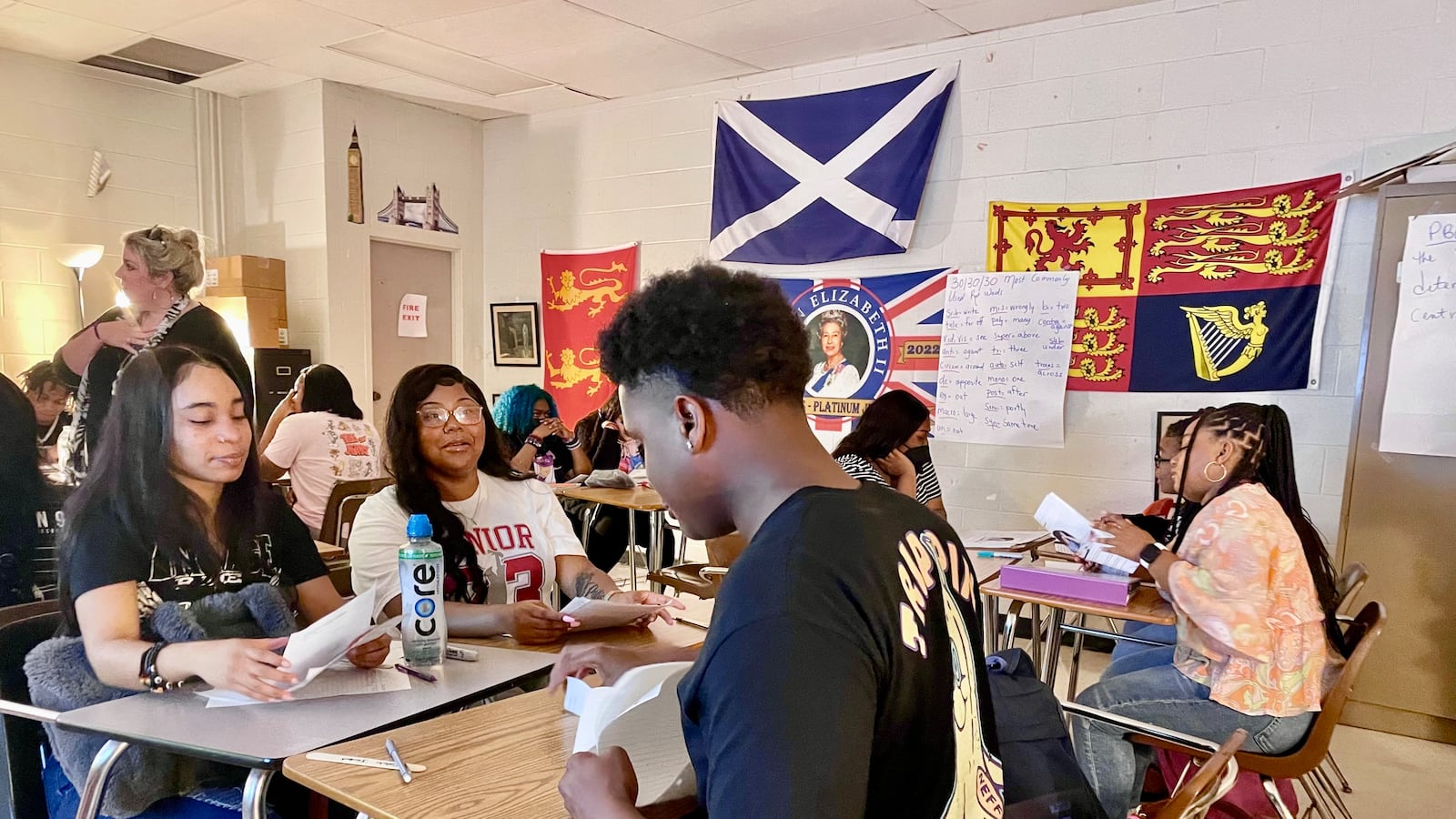 Students sit in desks arranged in groups of four in a classroom