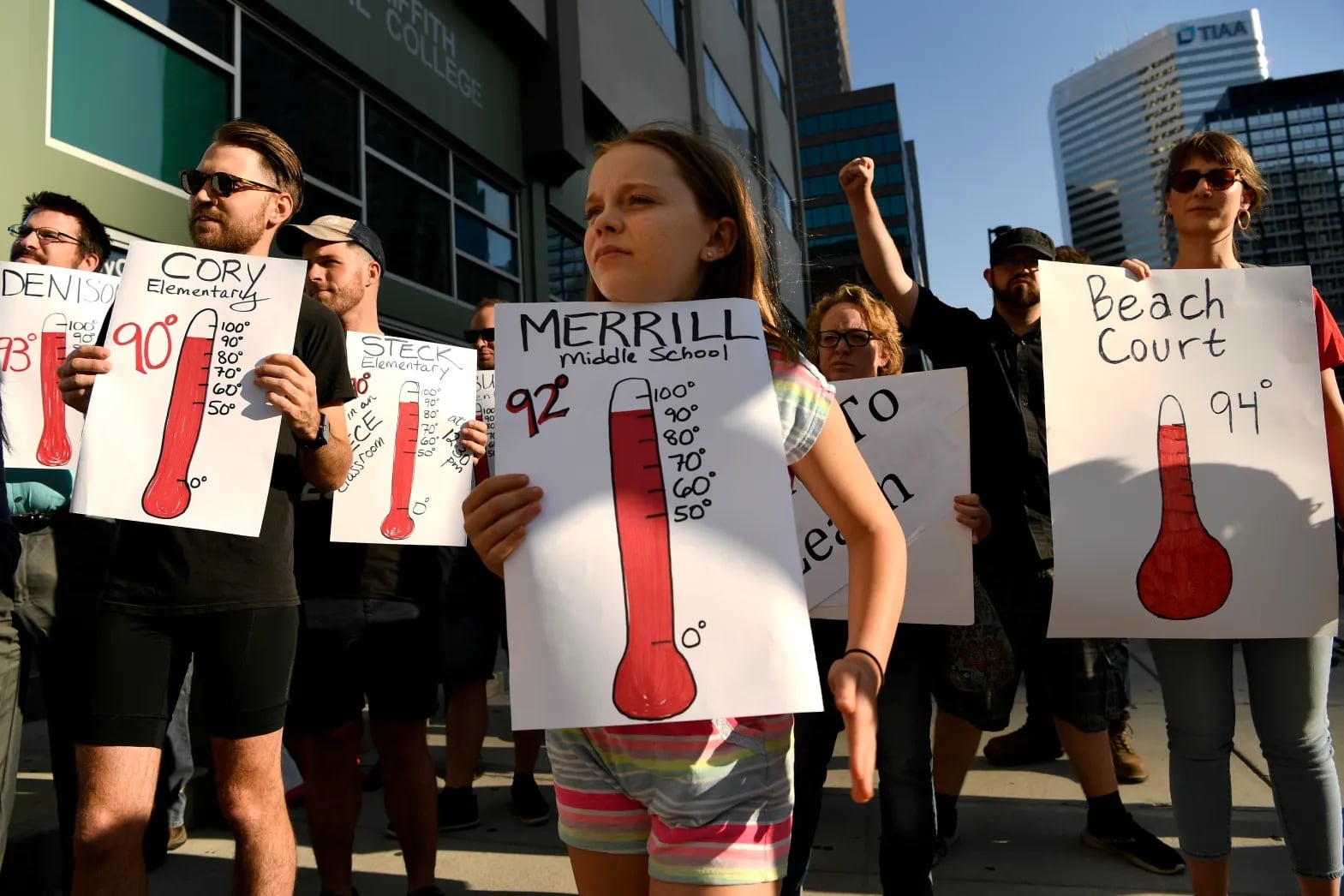 Young students hold posters showing images of thermometers to protest hot temperatures in their schools.