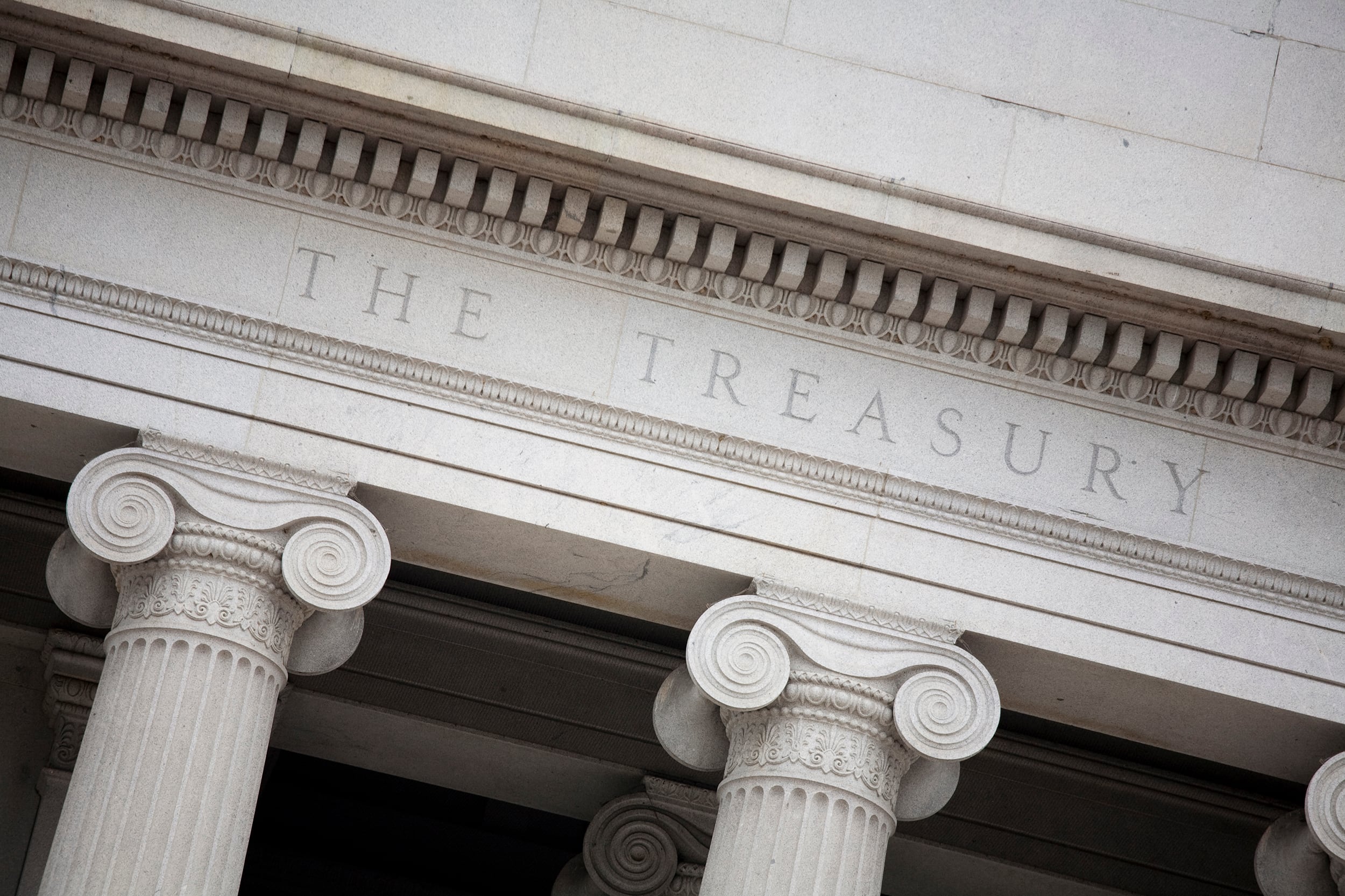 A photograph of part of a large white stone building with carved words that read "The Treasury."