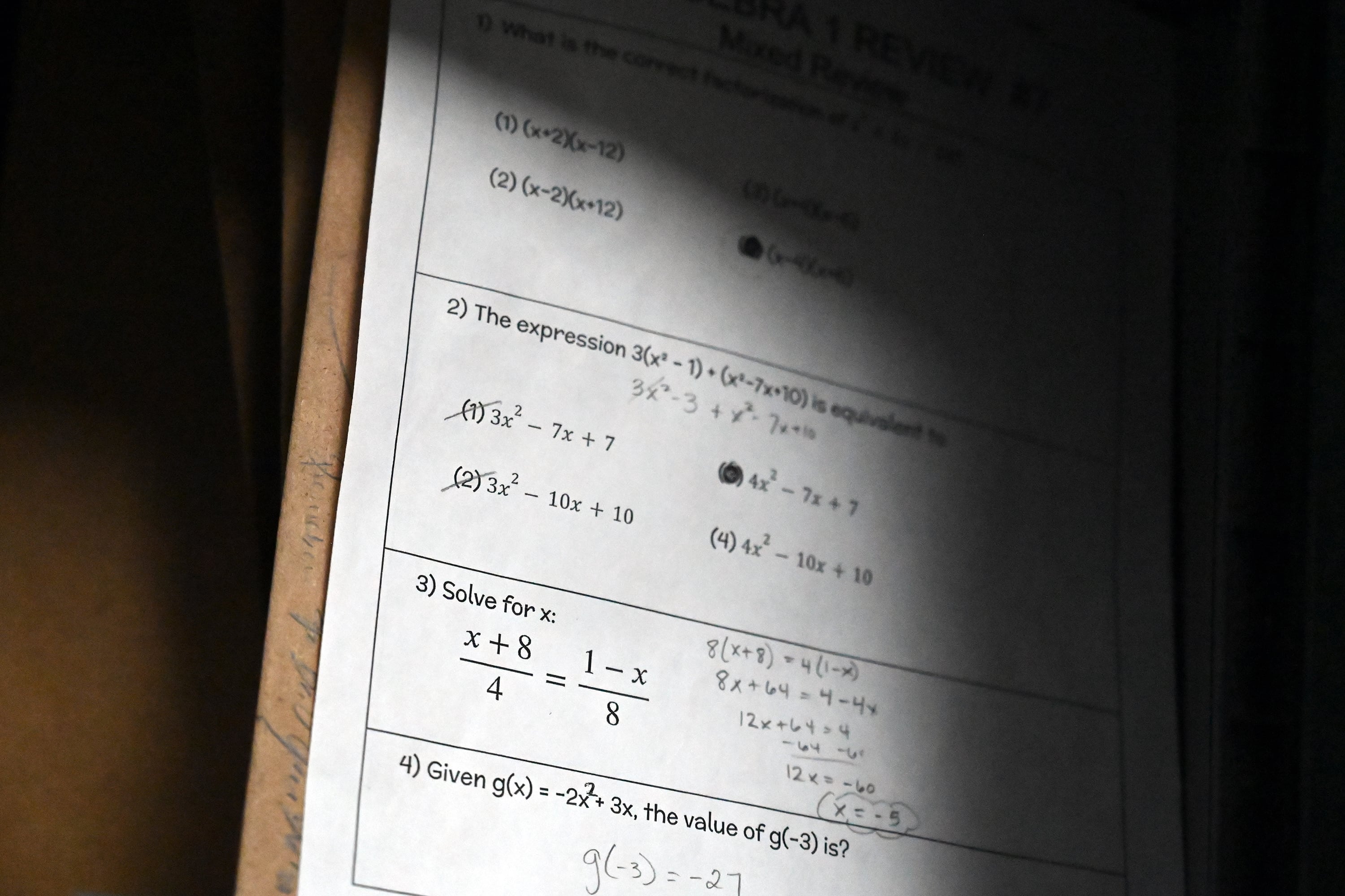 A piece of paper with a practice test of math equations sits on a desk.