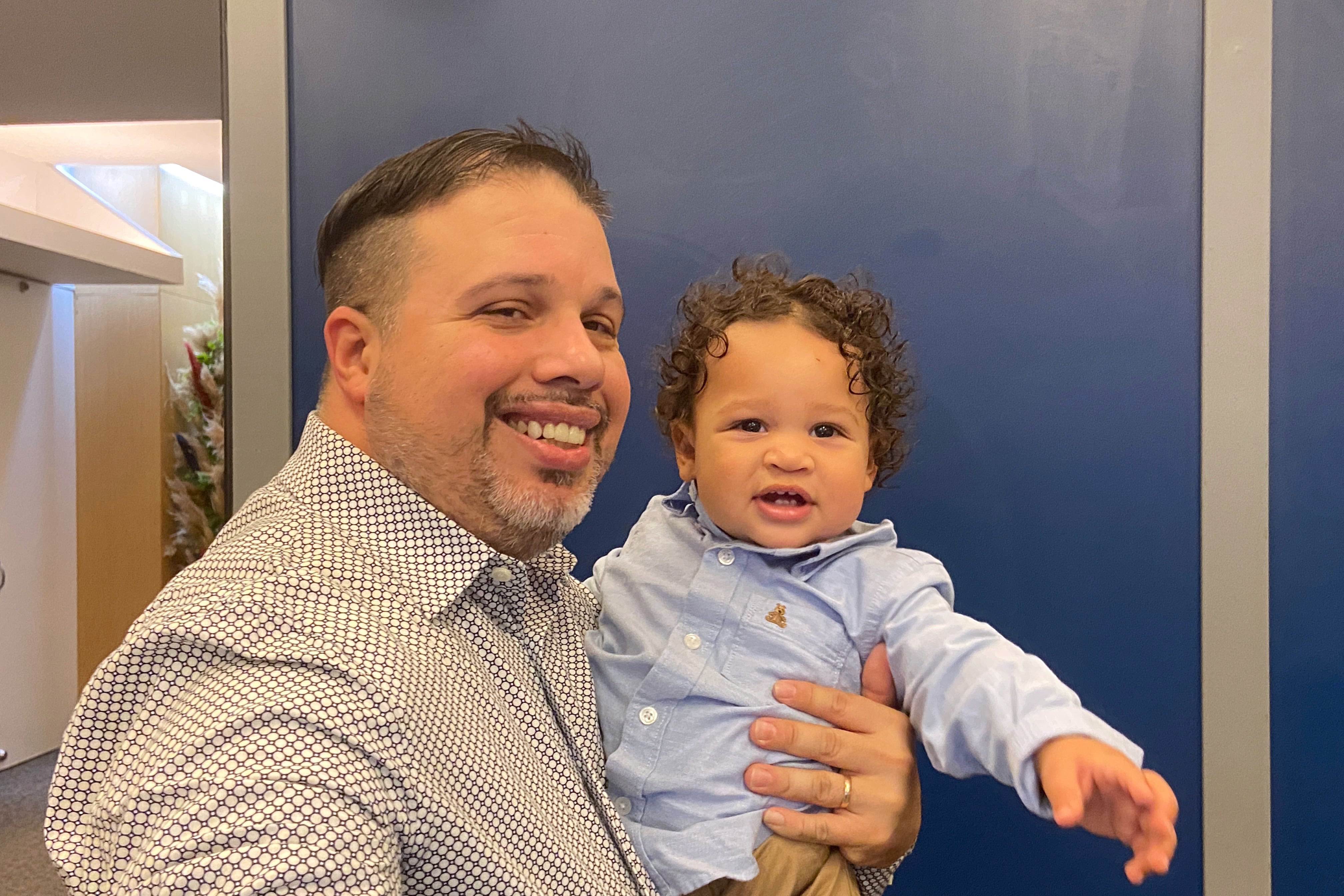 A photograph of a man holding his young son and posing for a photograph.