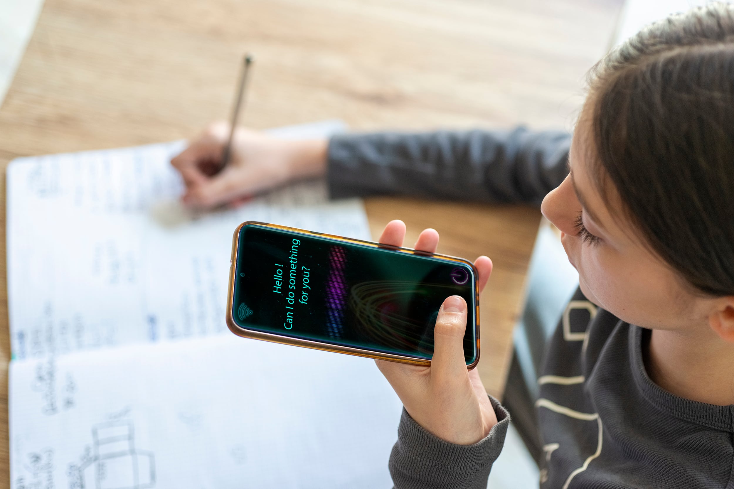 A photograph of a young girl using AI virtual assistant to do schoolwork.