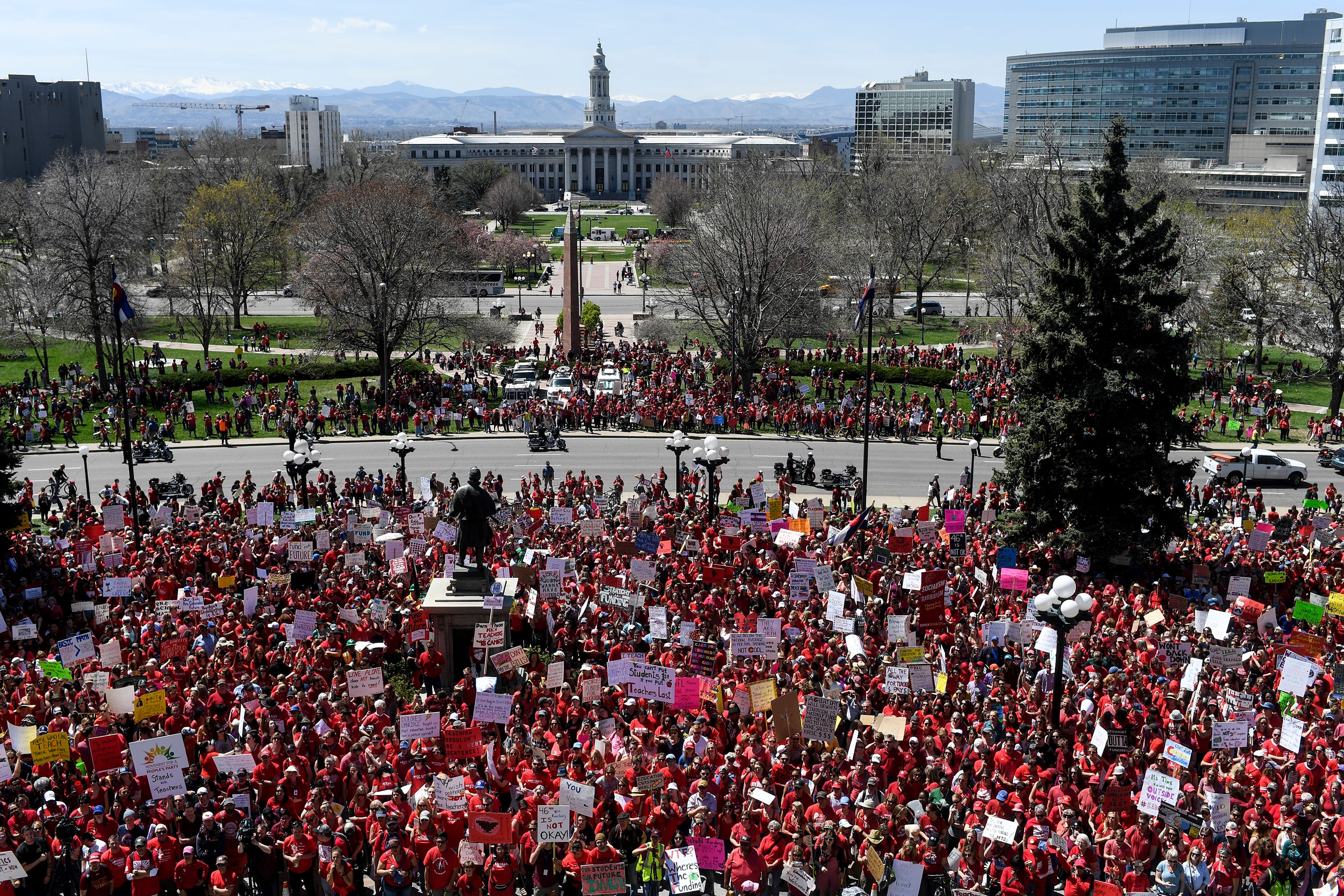 A view of the Colorado State Capitol building in the background with a sea of people protesting and majority wearing red shirts.