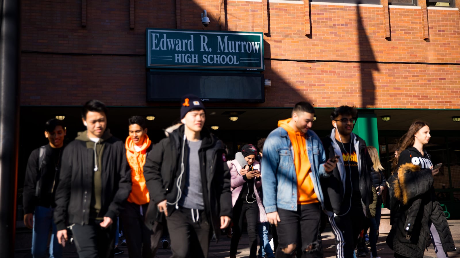 Students file out of a brick building labeled Edward R. Murrow High School