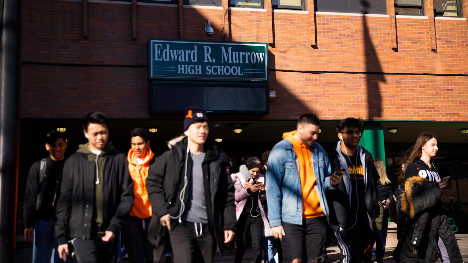 Students file out of a brick building labeled Edward R. Murrow High School