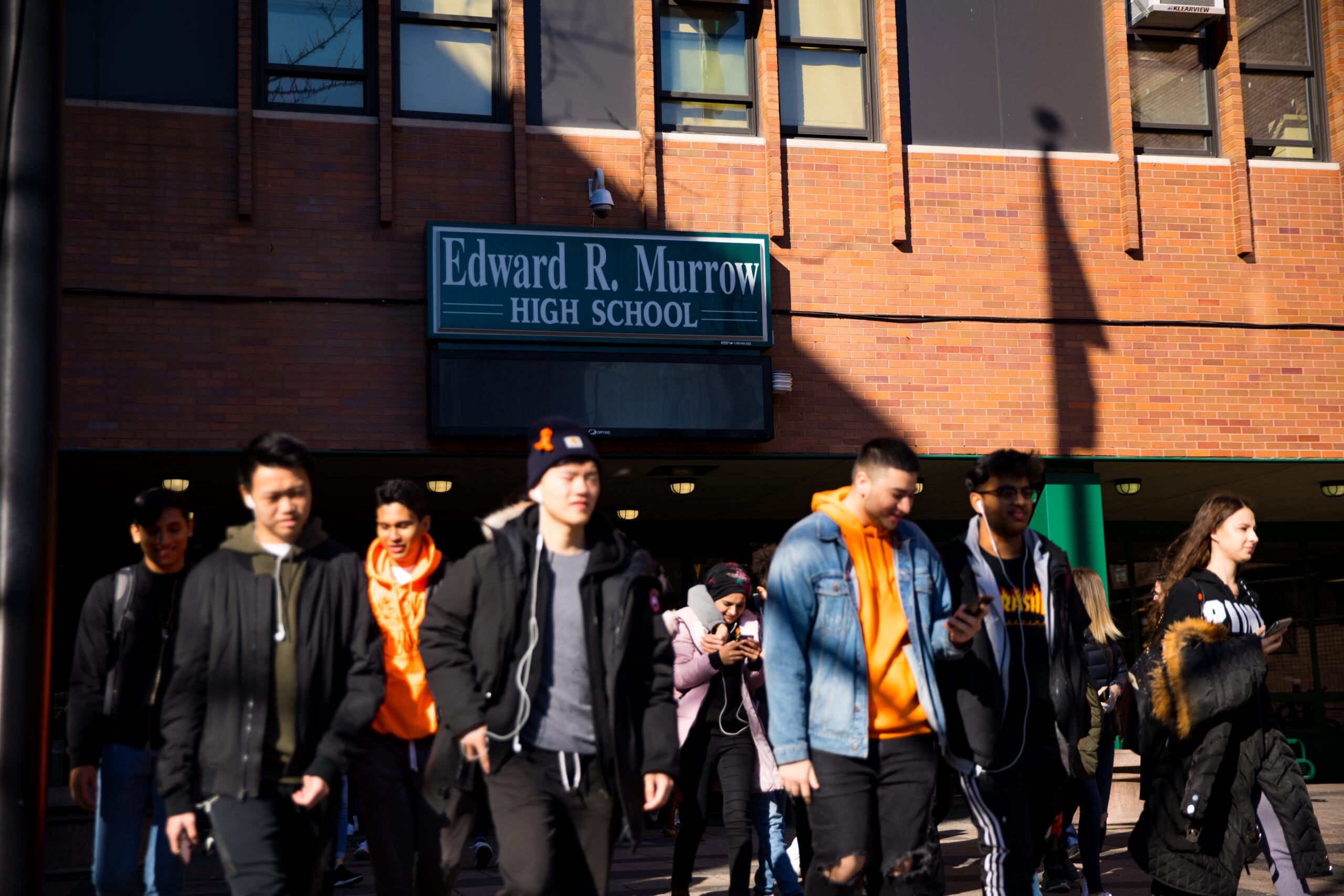 Students file out of a brick building labeled Edward R. Murrow High School
