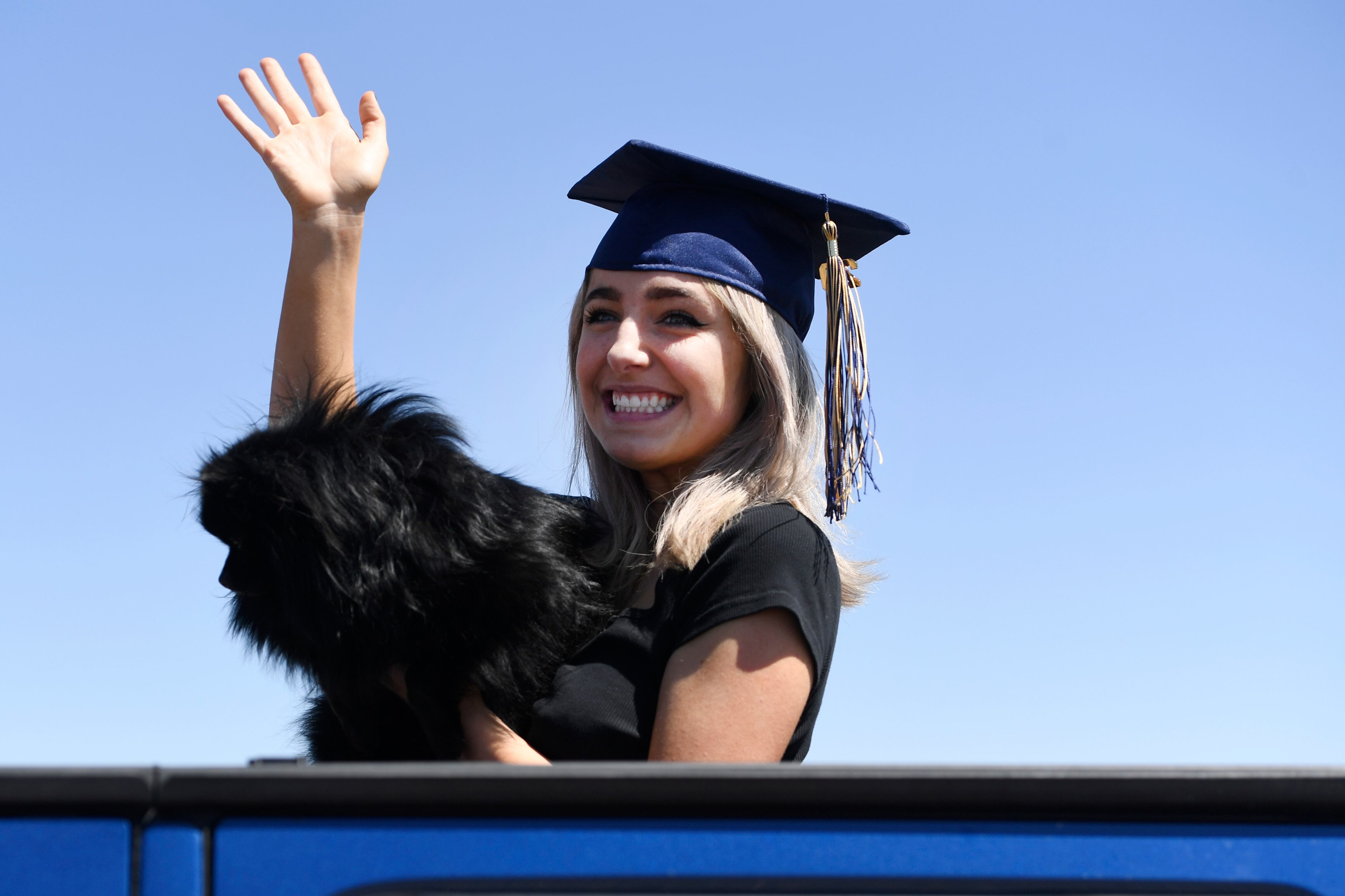 Legacy High School grad Ryen Hilton waves to teachers while holding her dog, Koda, during a senior appreciation car parade on Thursday, May 21.