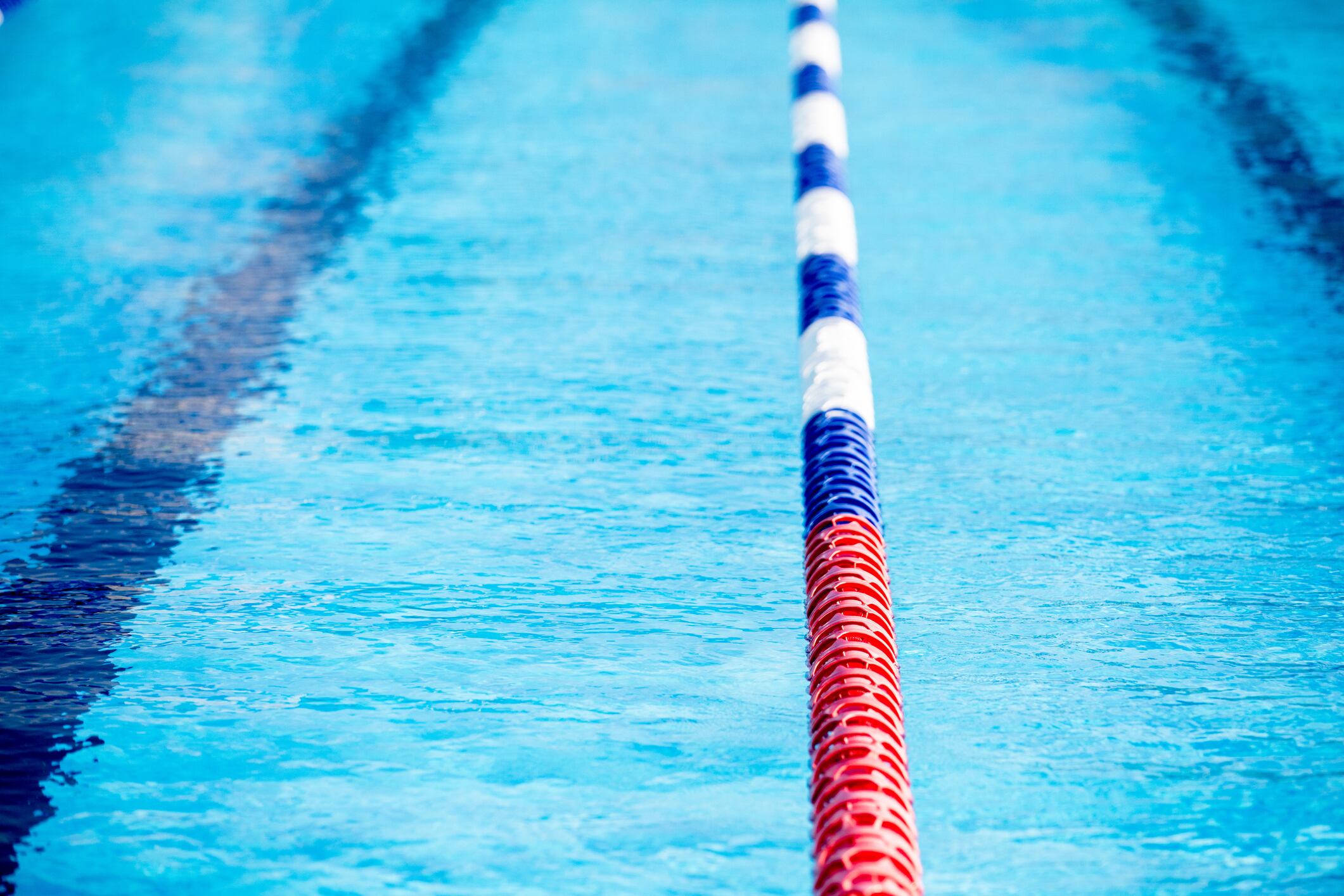 A swimming pool lane marked by blue, red, white dividers. 