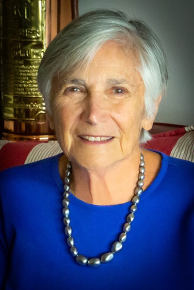 A portrait of a woman with short, gray hair and a blue top.
