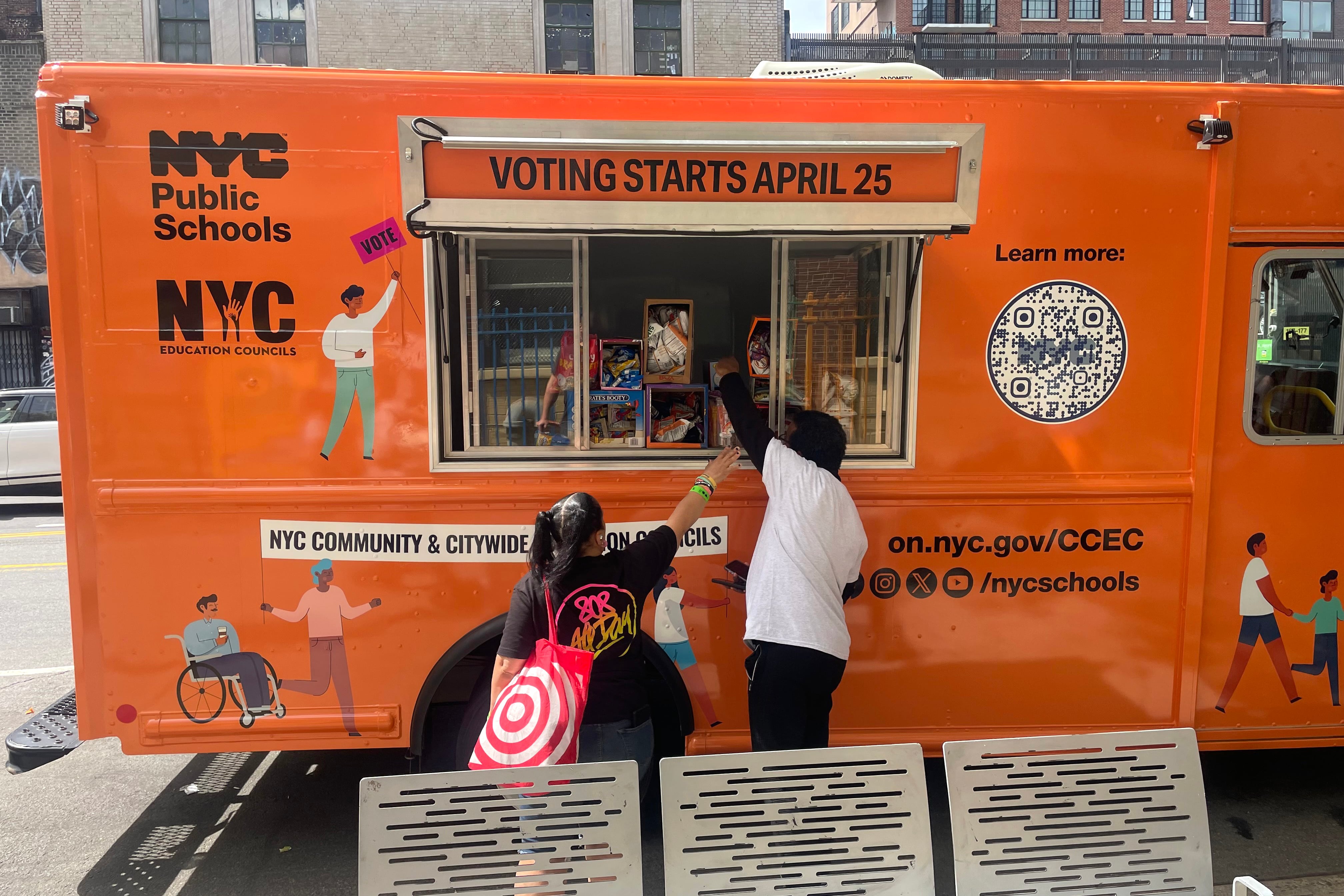People stand next to an orange truck.
