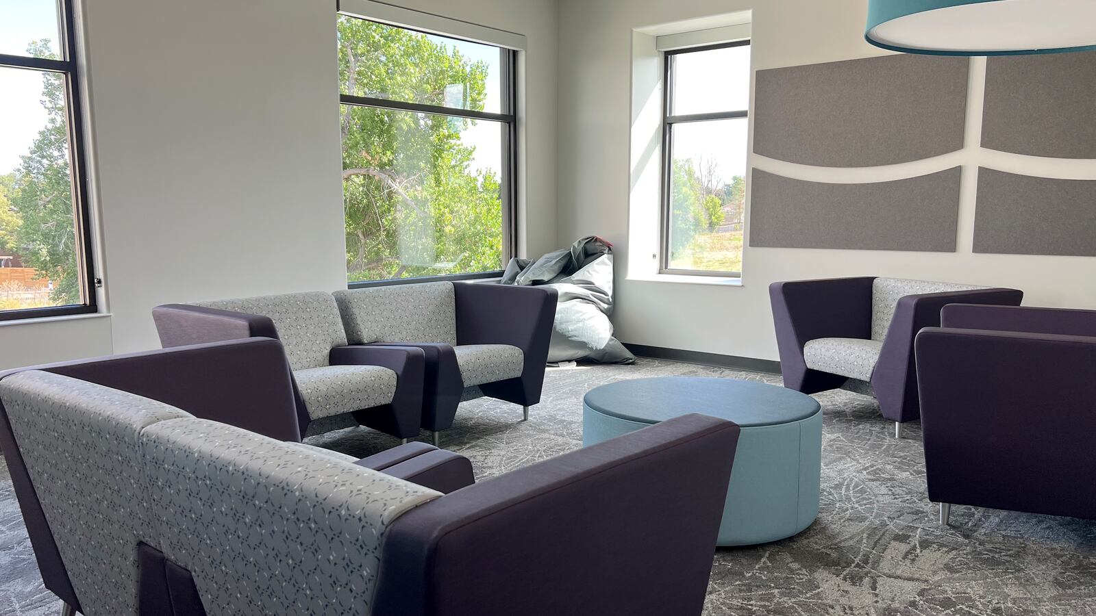 A seating area with purple couches and chairs in a room with large windows.